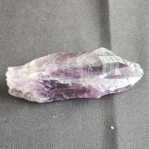 Auralite 23 crystal with deep purple amethyst tones and complex internal mineral inclusions, showing a raw, high-vibration crystalline structure.