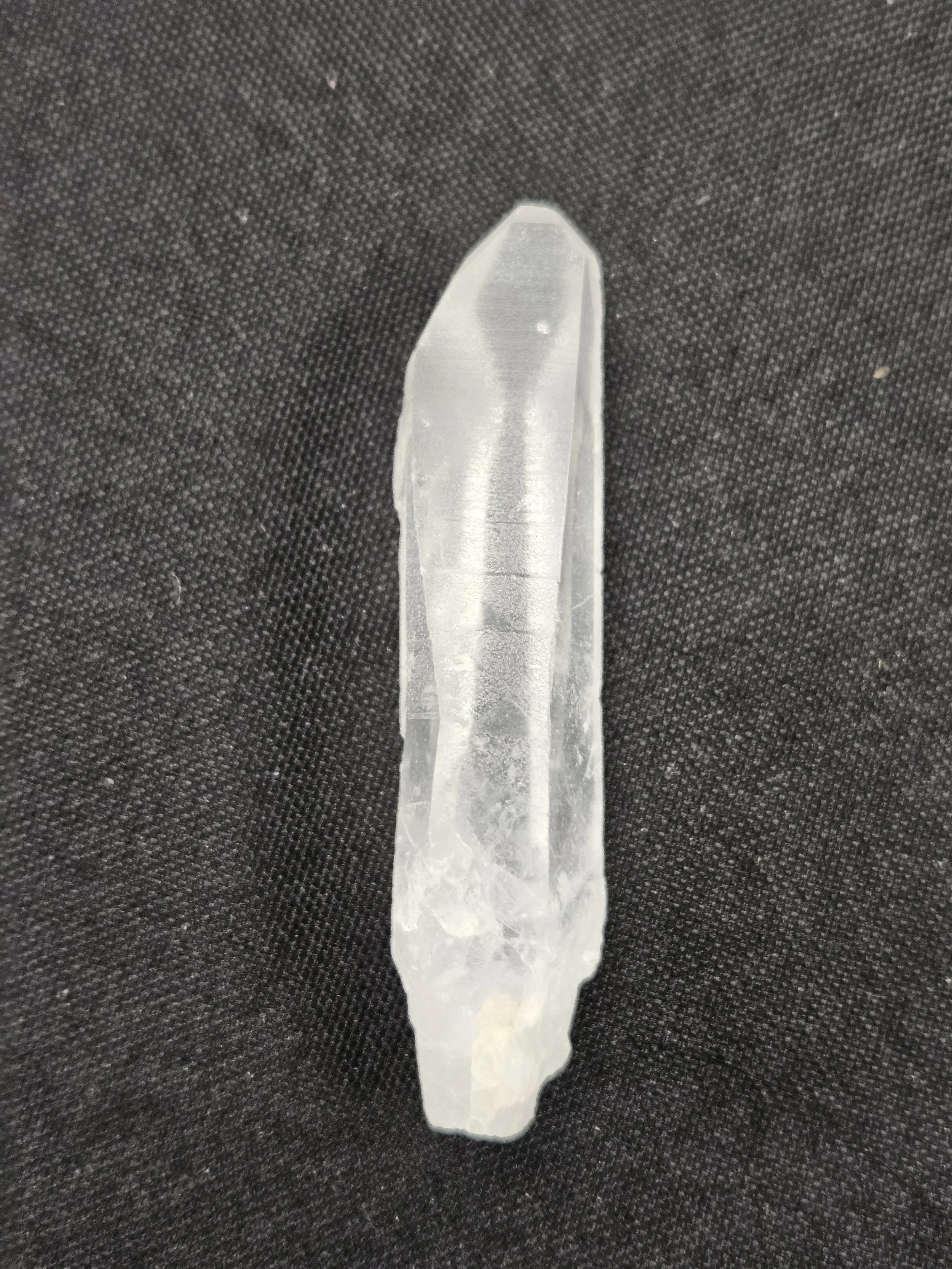 Clear Lemurian quartz crystal point showing distinctive horizontal ladder-like striations along its natural faces.