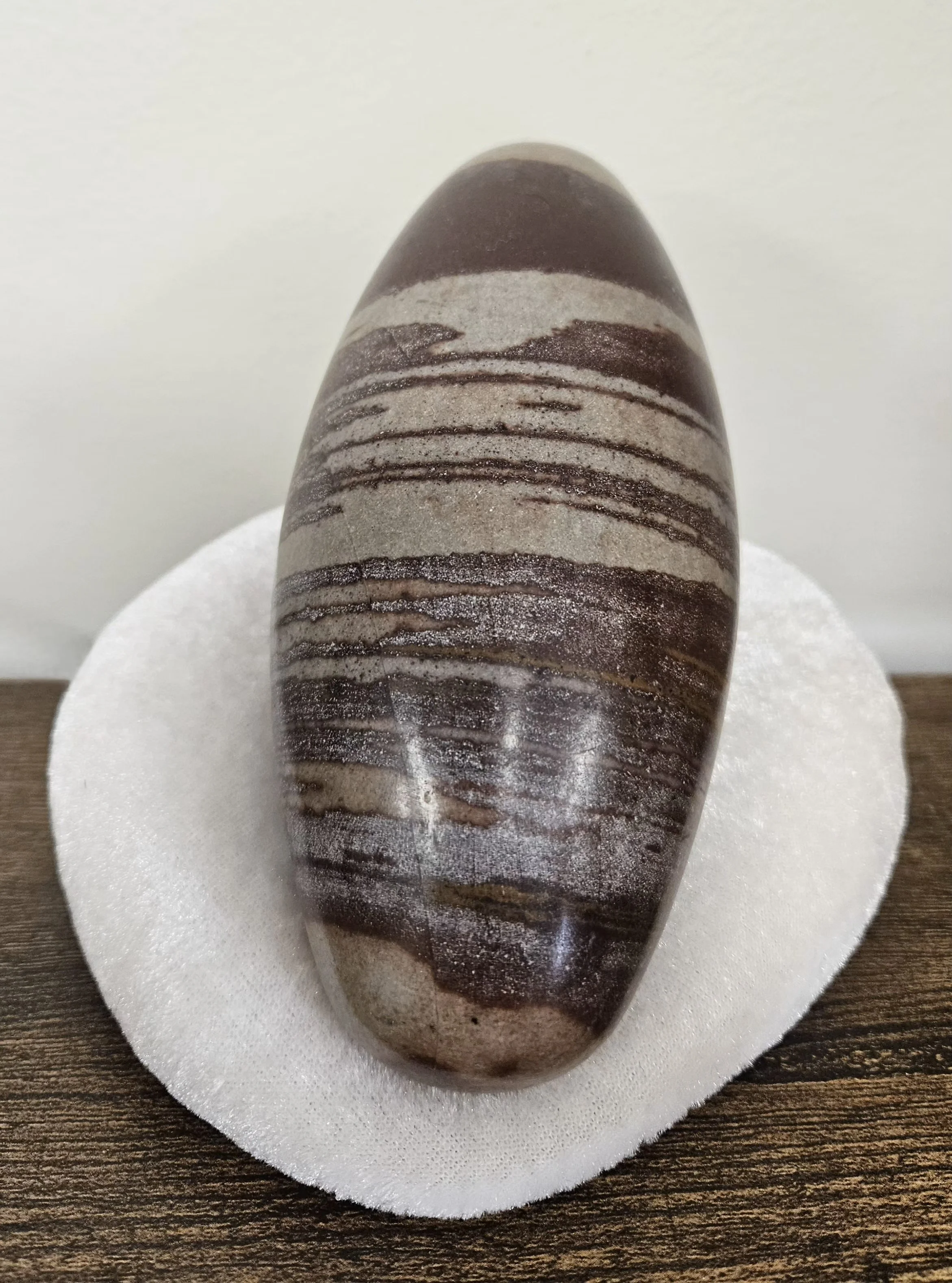 Polished Shiva Lingam stone with natural brown and reddish markings in an egg-shaped form.