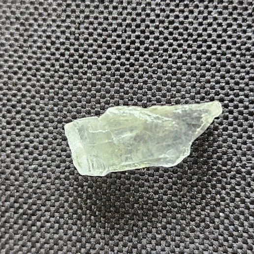 Small translucent phenacite crystal with natural facets and bright reflective clarity.