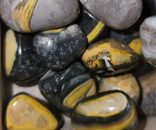 A Bumble Bee Jasper stone with striking bands of yellow, orange, and black in bold, natural patterns.
