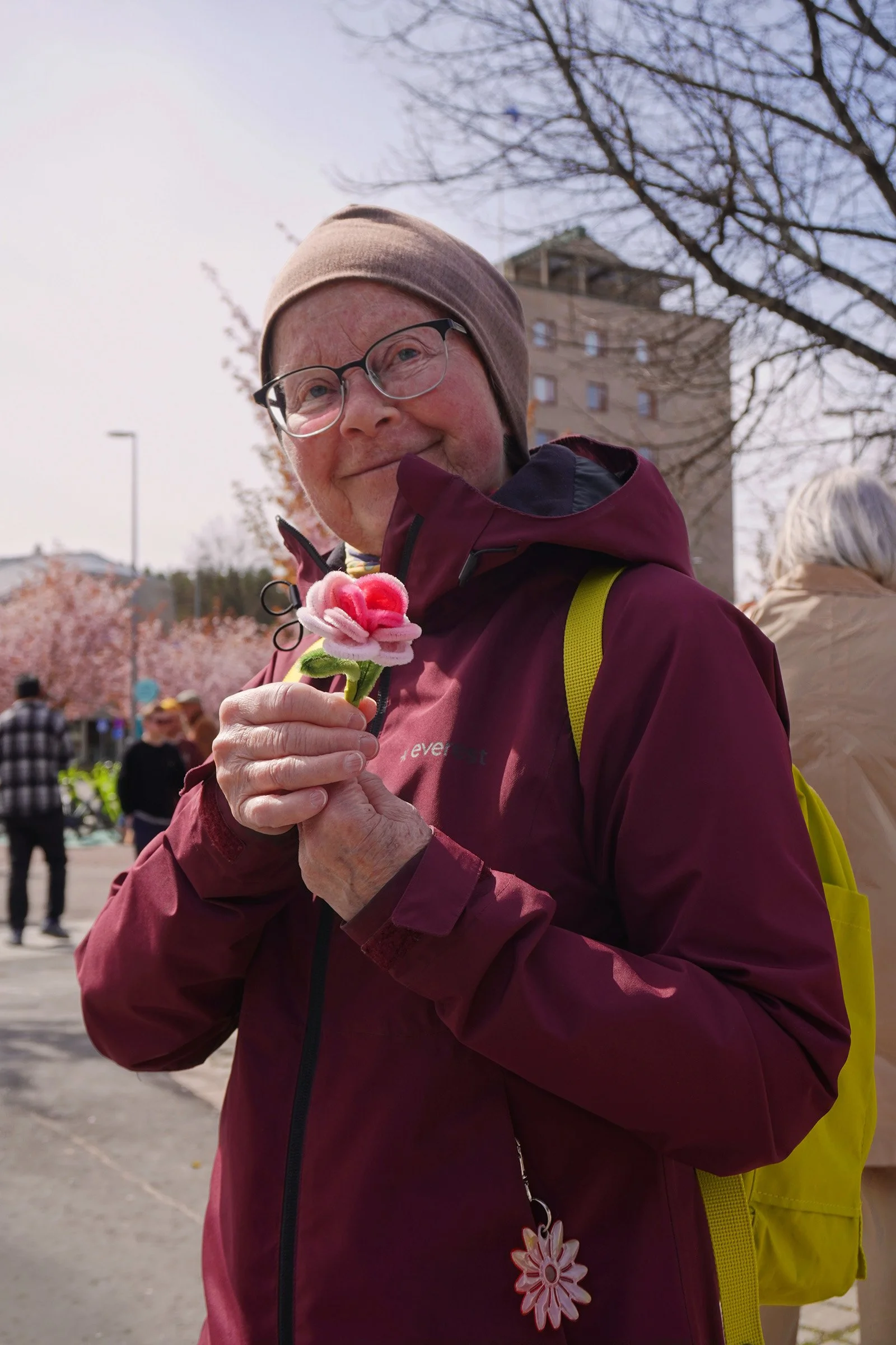 An older visitor smiling after receiving a handmade flower during the event.