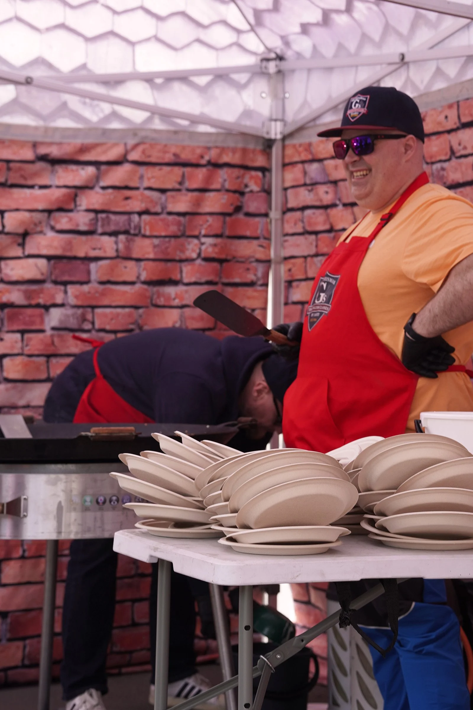A volunteer preparing pancakes while visitors gathered around the festival area.