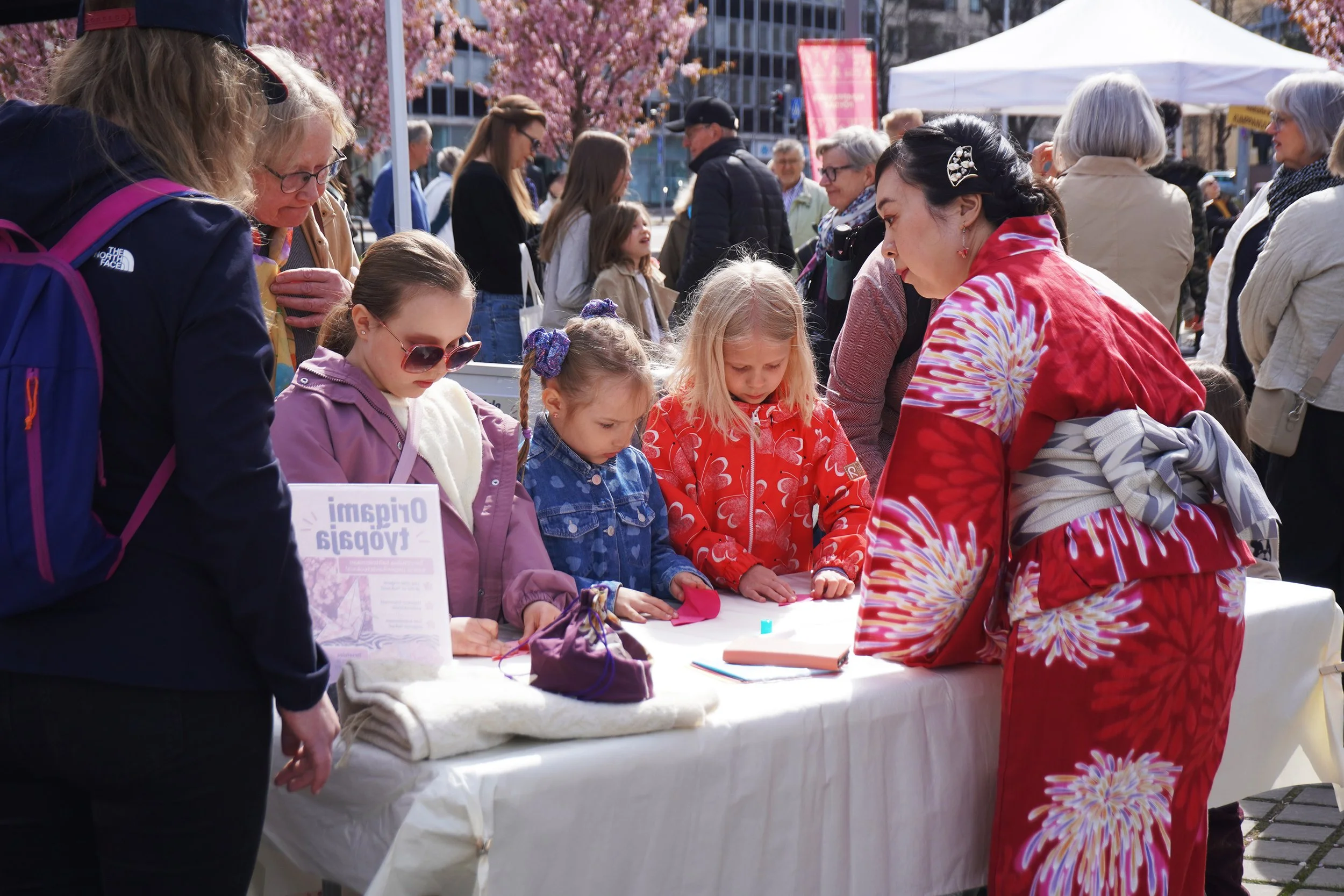Visitors participating in a Japanese-inspired creative activity under the cherry blossoms.