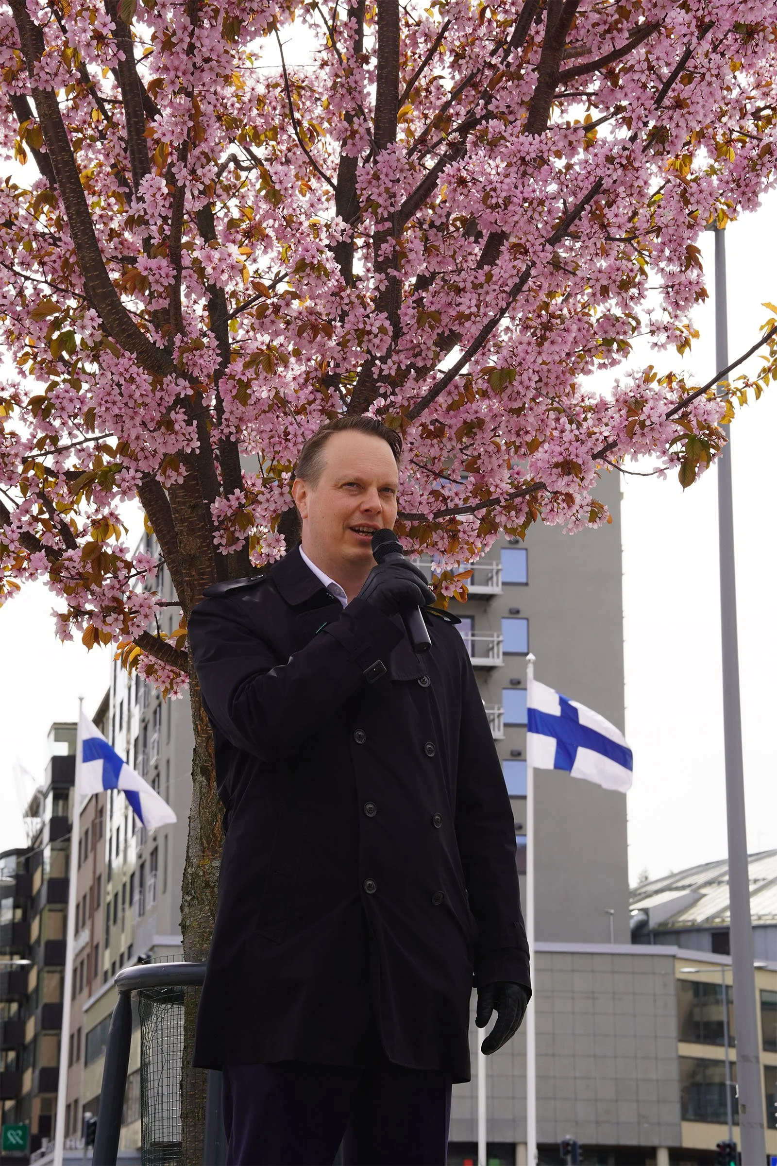 The mayor of Lahti giving the closing speech beneath the cherry blossom trees at the end of the event.
