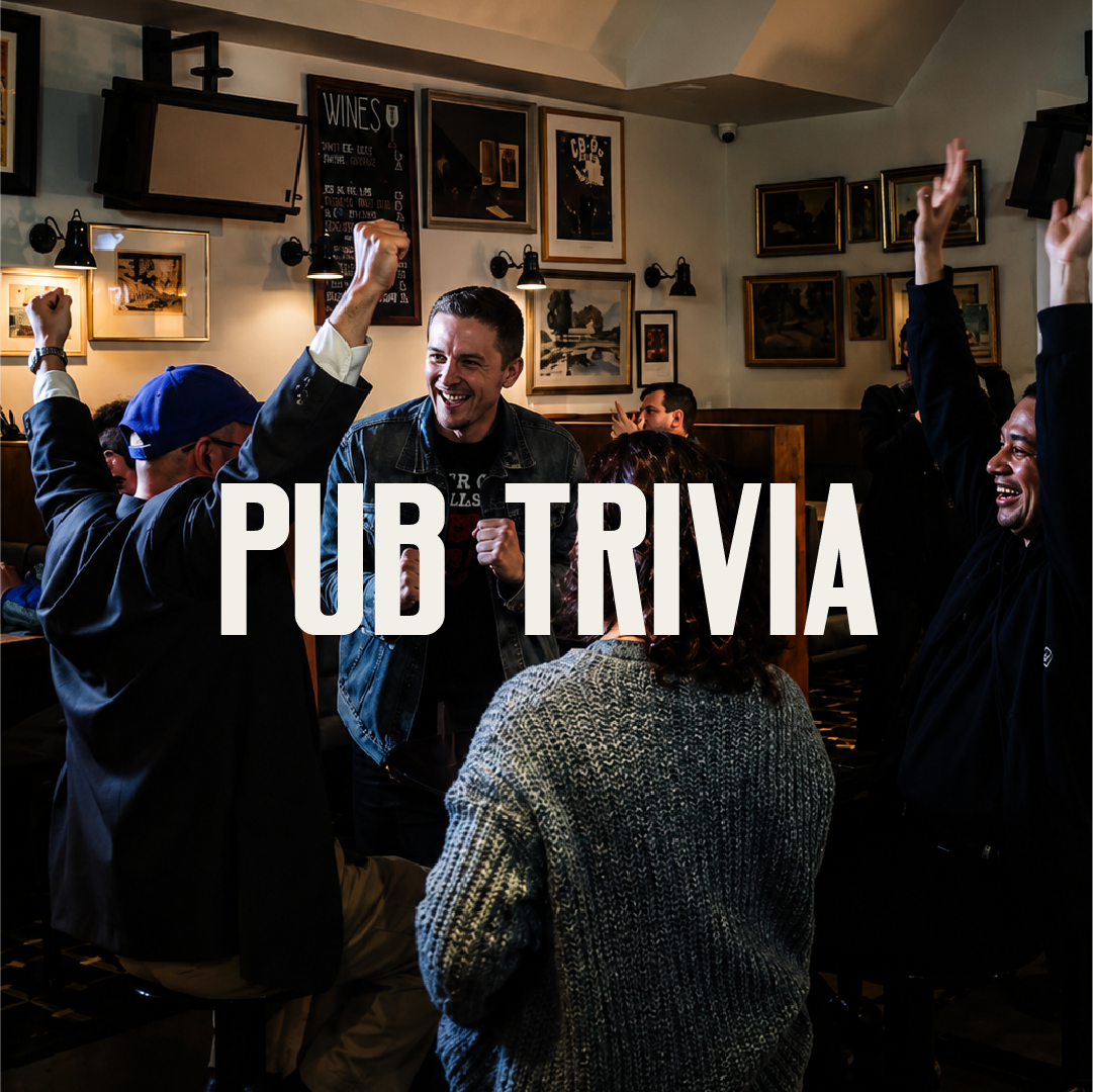 People celebrating and playing pub trivia in a cozy bar with framed pictures and a chalkboard menu.