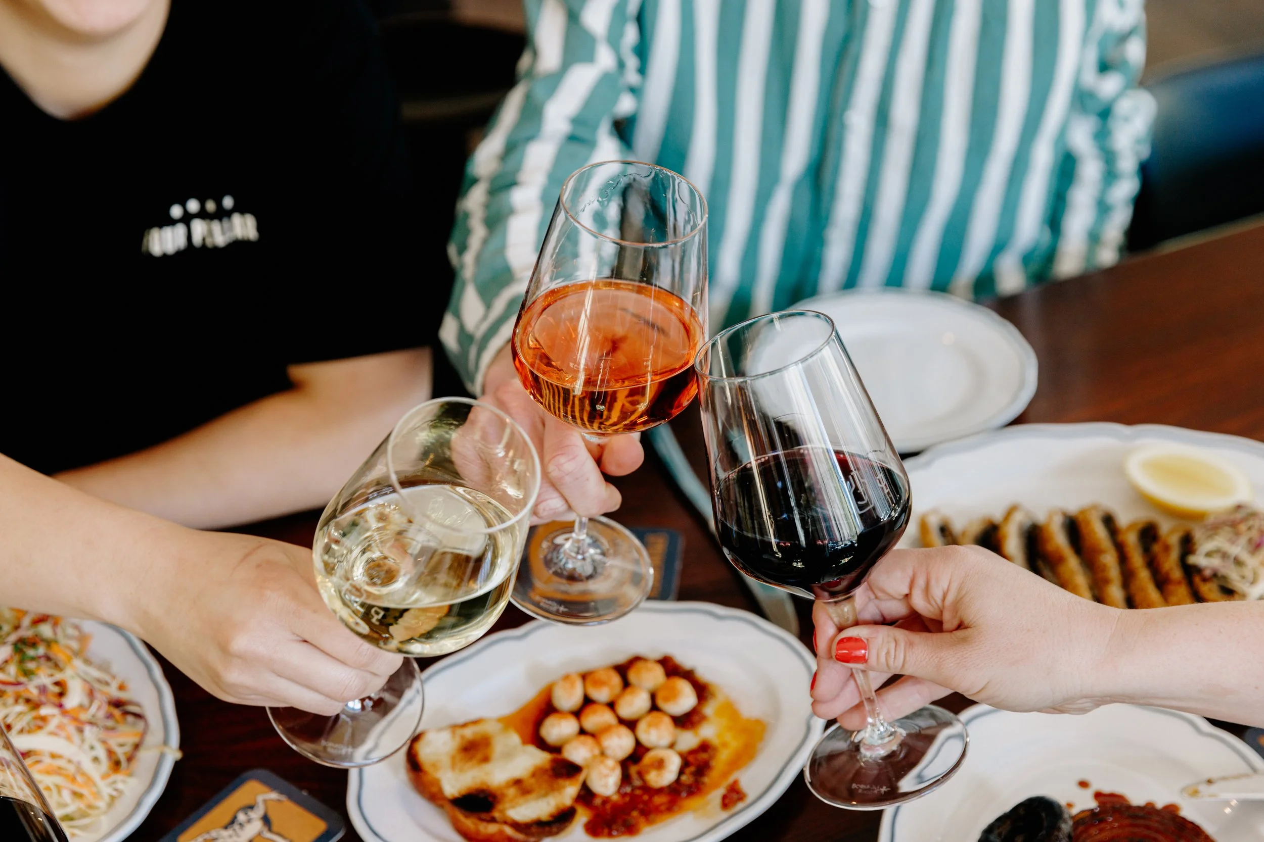 Friends clinking glasses of rosé, white and red wine over dinner at Springrock