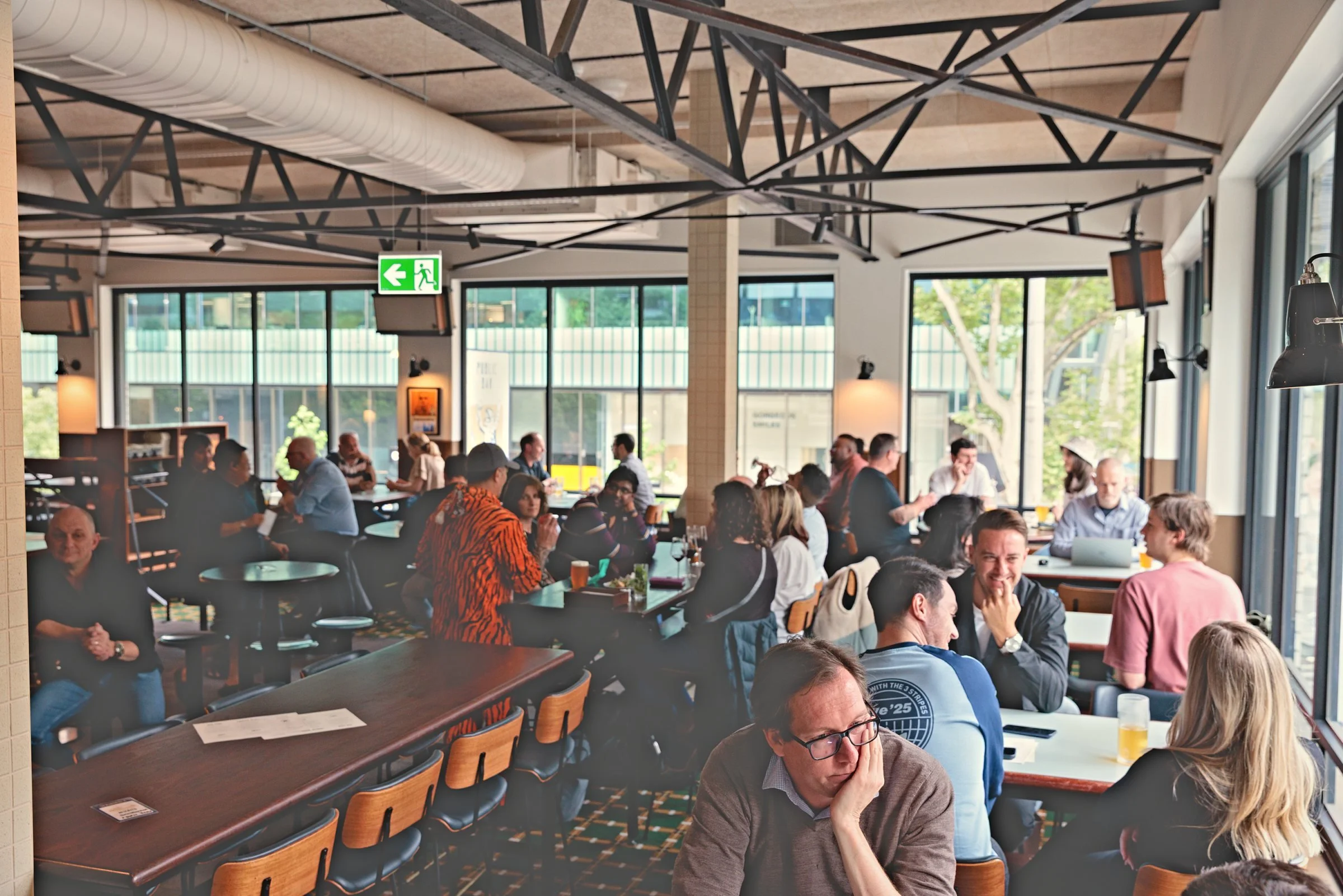 The Springrock dining room on a busy afternoon, with steel trusses overhead and big windows onto Bourke Street