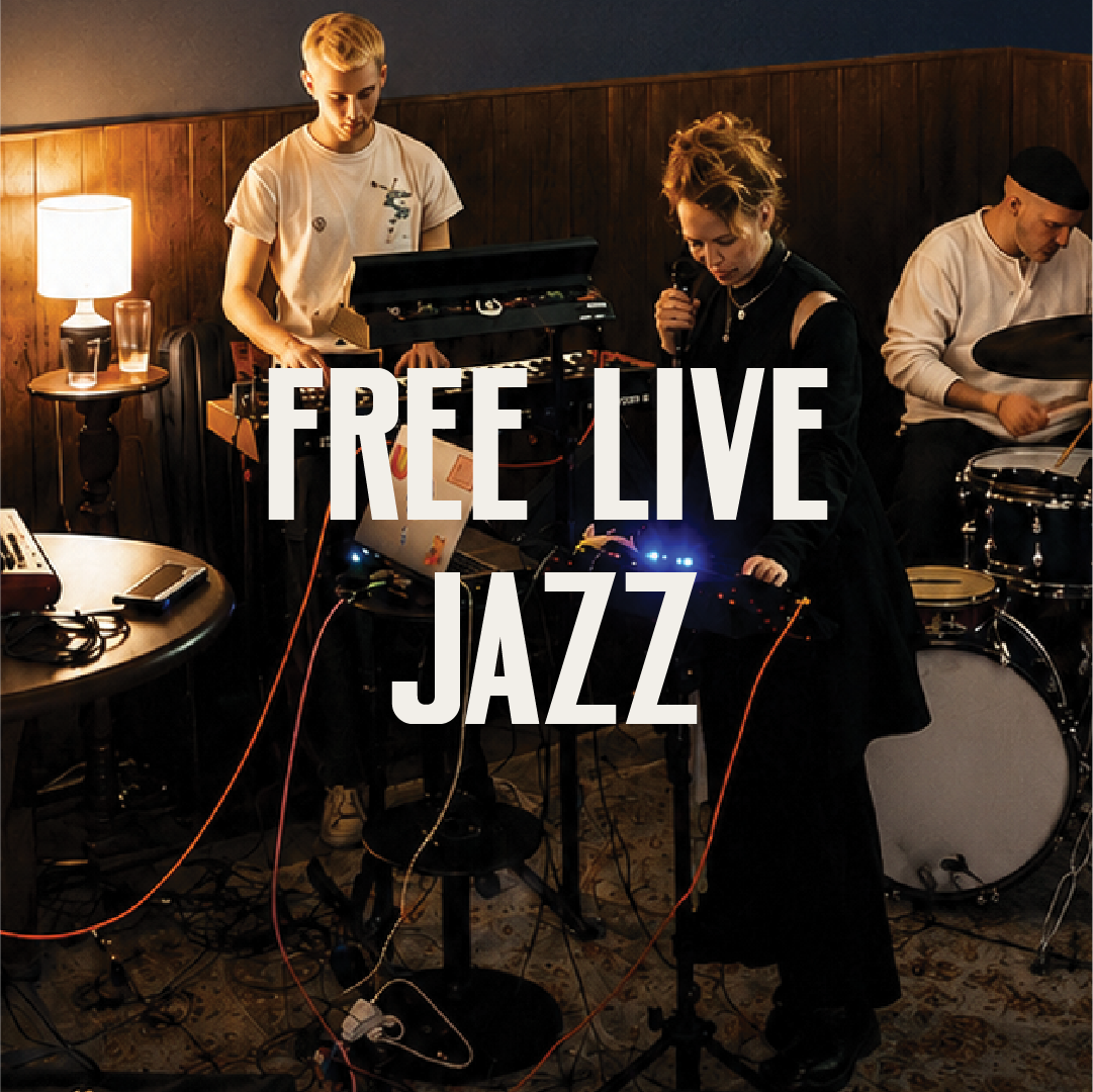 Three musicians perform in a dimly lit room, with one at a keyboard, one at a drum set, and one with a microphone, with text overlay saying "Free Live Jazz."