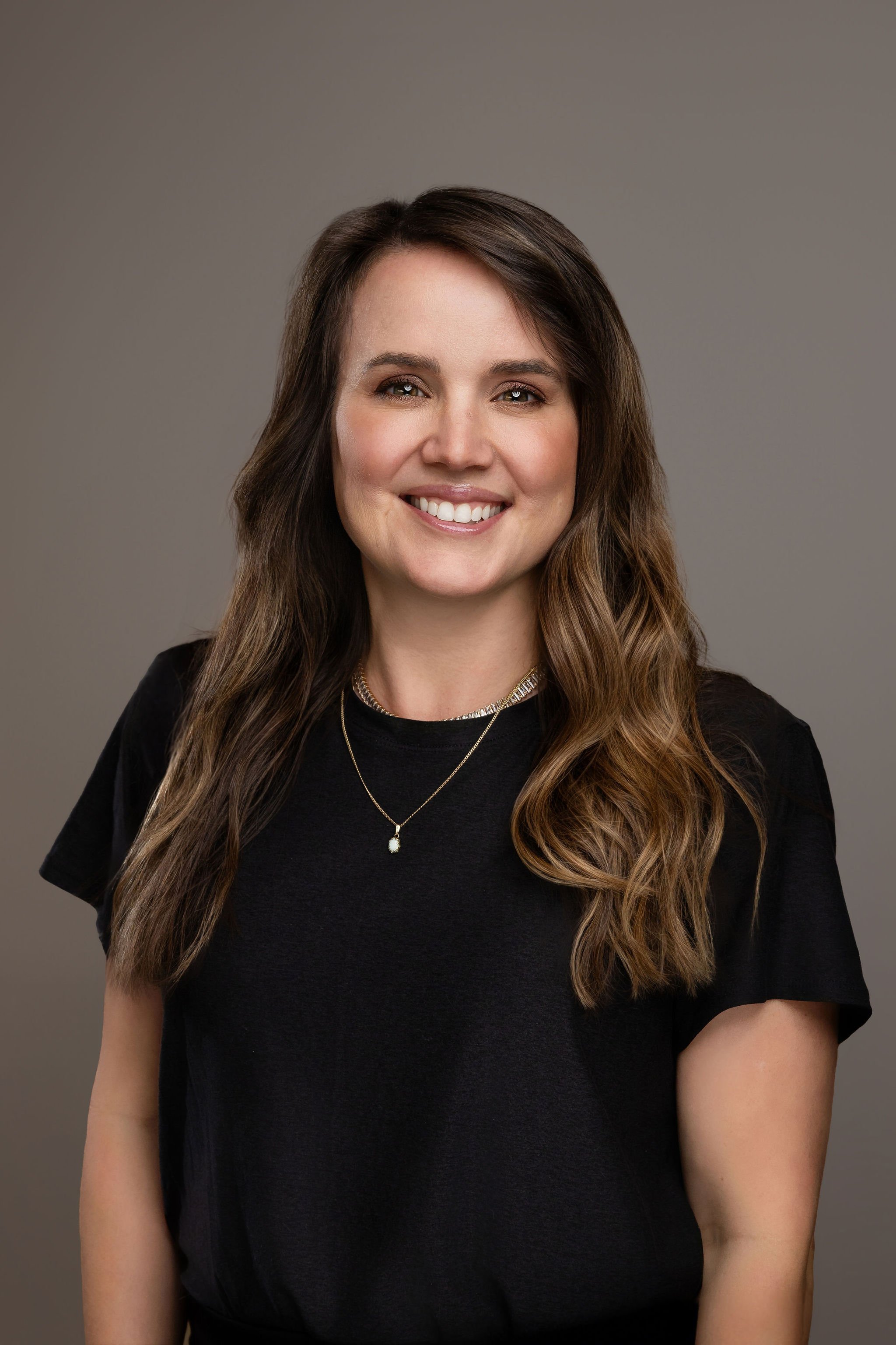 Sara Hamlin, aesthetic nurse at The Collective Salon & Med Spa in Tennessee, smiling in black scrubs against a light background