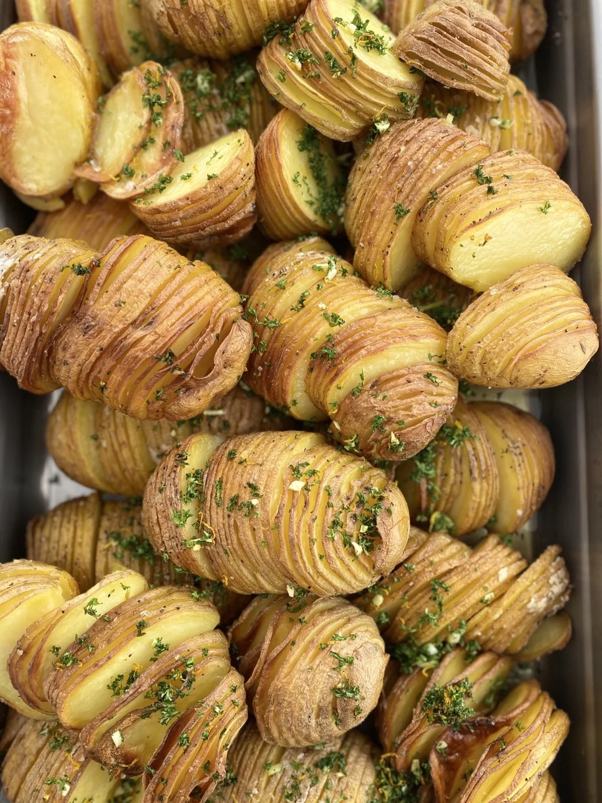 Roasted Hasselback potatoes garnished with chopped parsley.