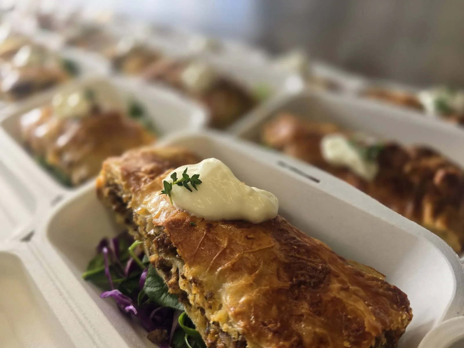 A close-up of a Serbian pie garnished with micro greens, with shredded purple cabbage underneath.
