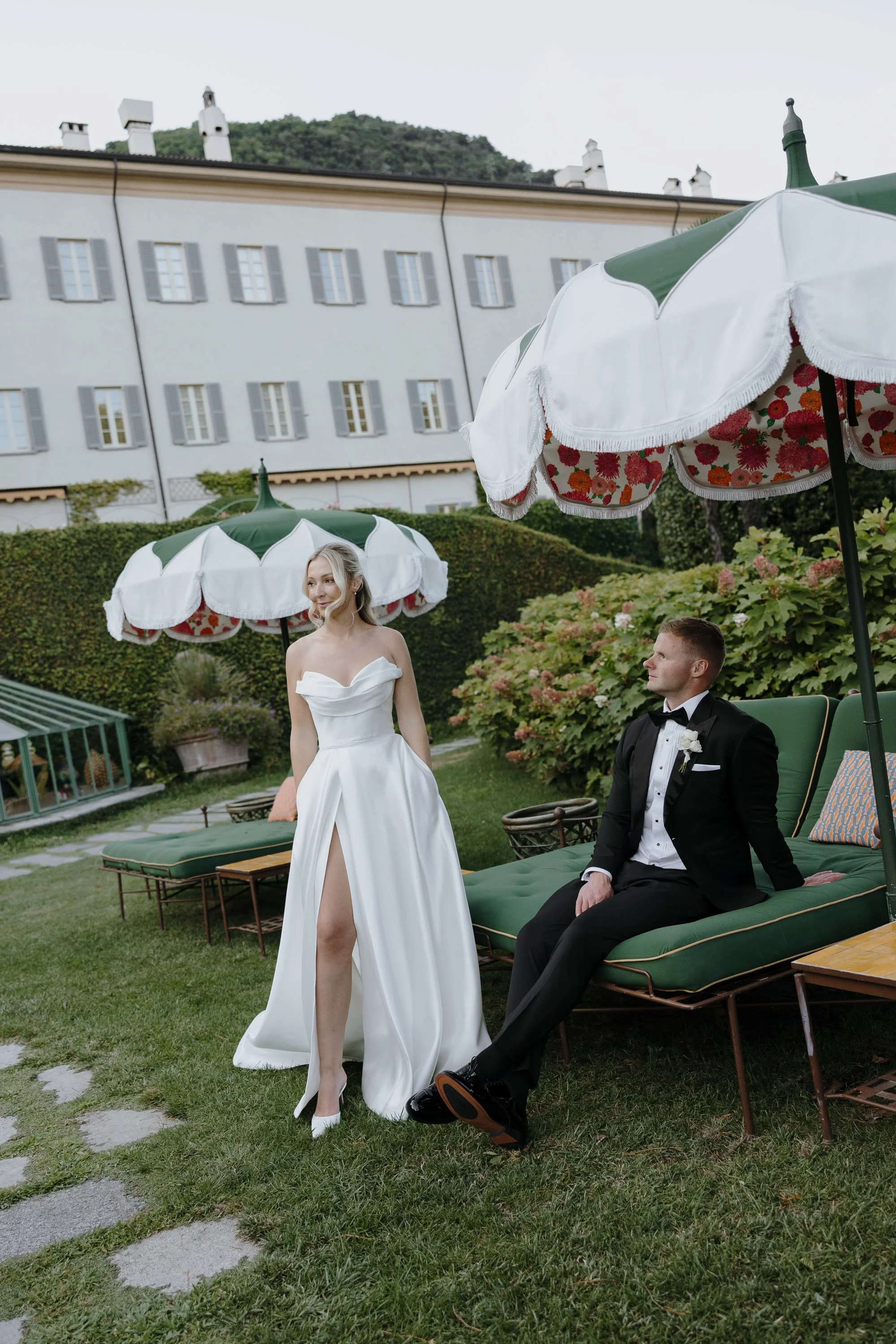 Lake Como elopement with the Elopement Collective.  A man and woman are posing for a wedding photo with umbrellas in the background.