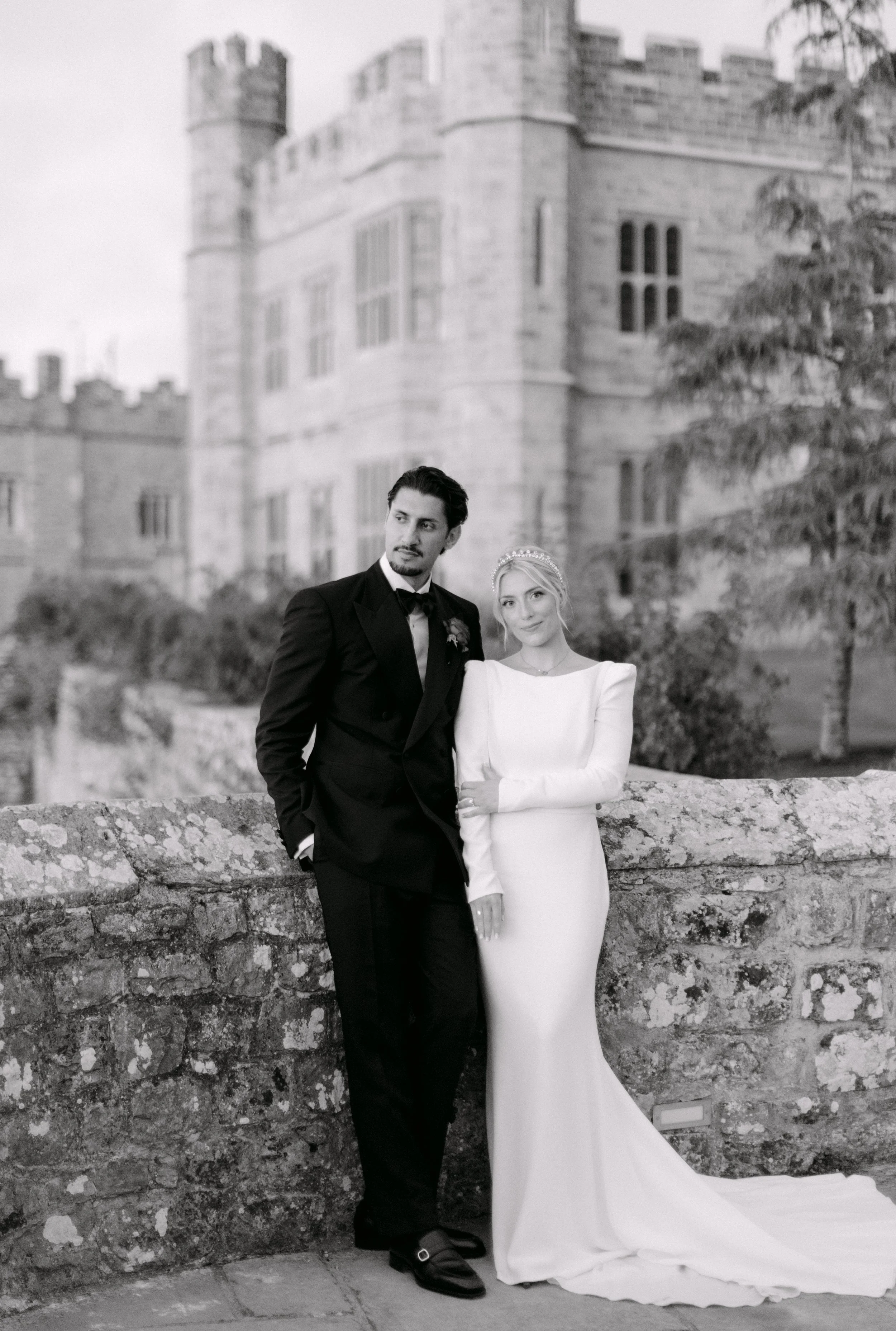 bri9de and groom standing next to leeds castle at their wedding 