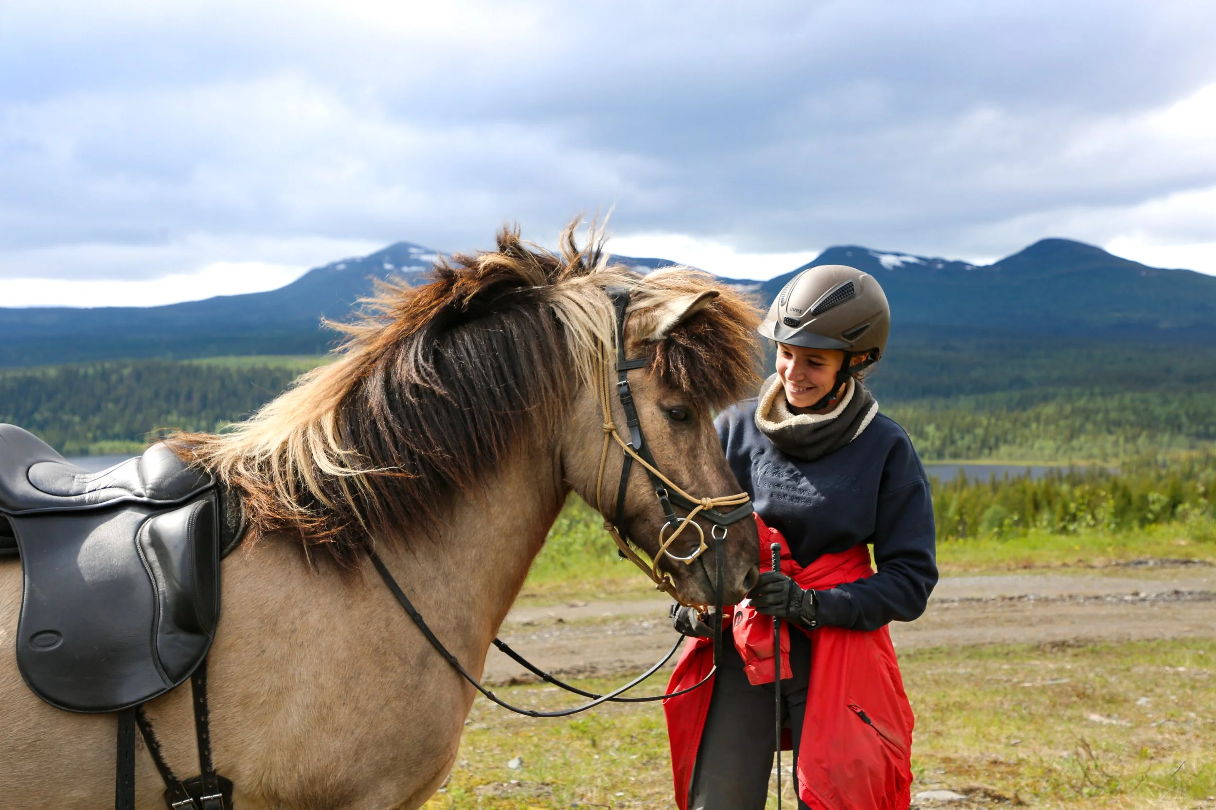 Woman caring for an Icelandic Horse with the Ansätten mountain in the background