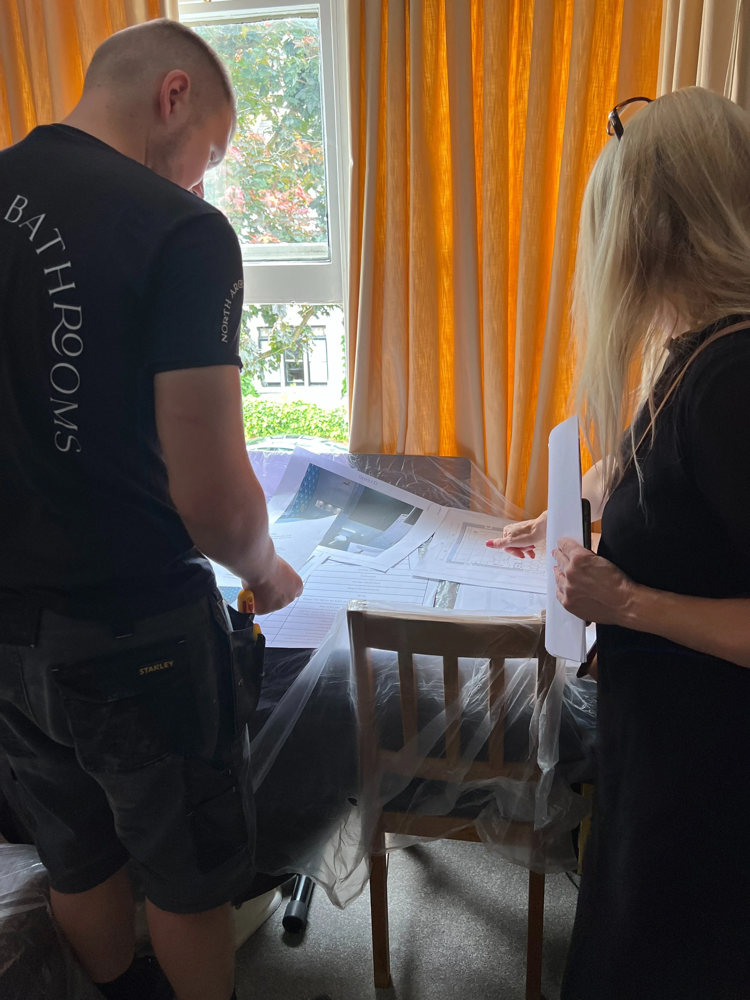 North Arch Bathrooms team reviewing design plans with a client during a site visit, discussing layout details and installation specifications before project commencement.