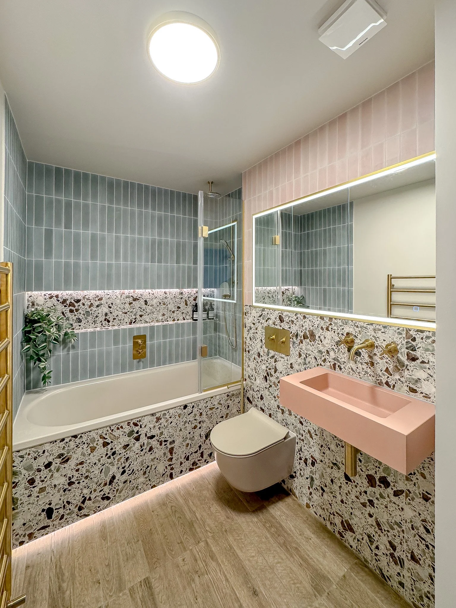 Terrazzo bathroom with blush pink basin, brass fittings and glass bath screen in North London