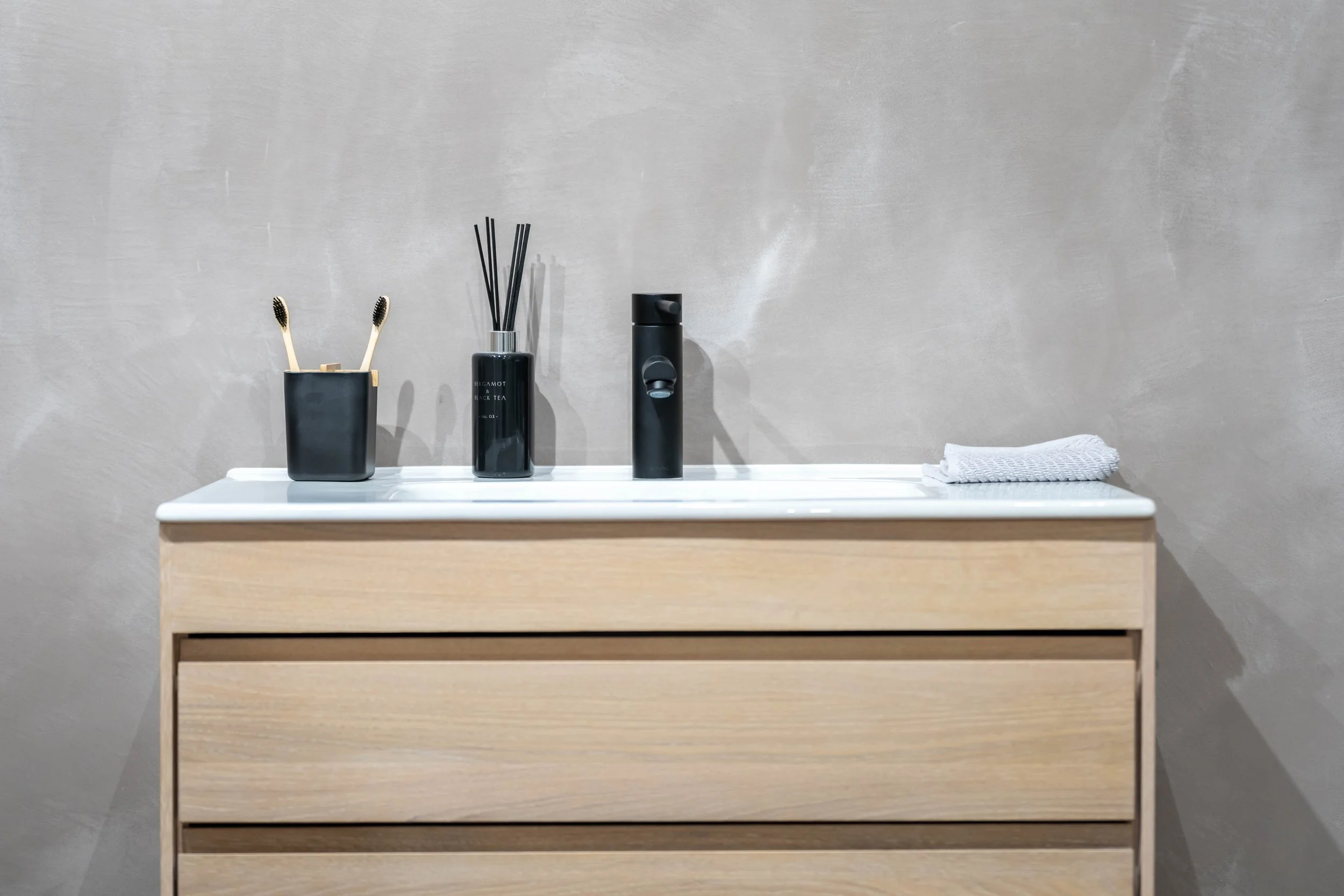 Minimalist bathroom vanity with timber cabinet, white basin and matte black tapware in North London