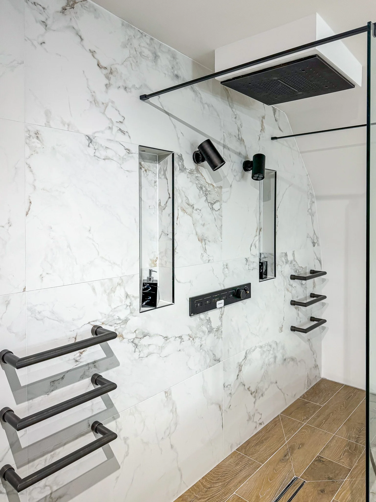 Luxury walk-in shower with marble-effect tiles, black fittings and recessed niches in North London