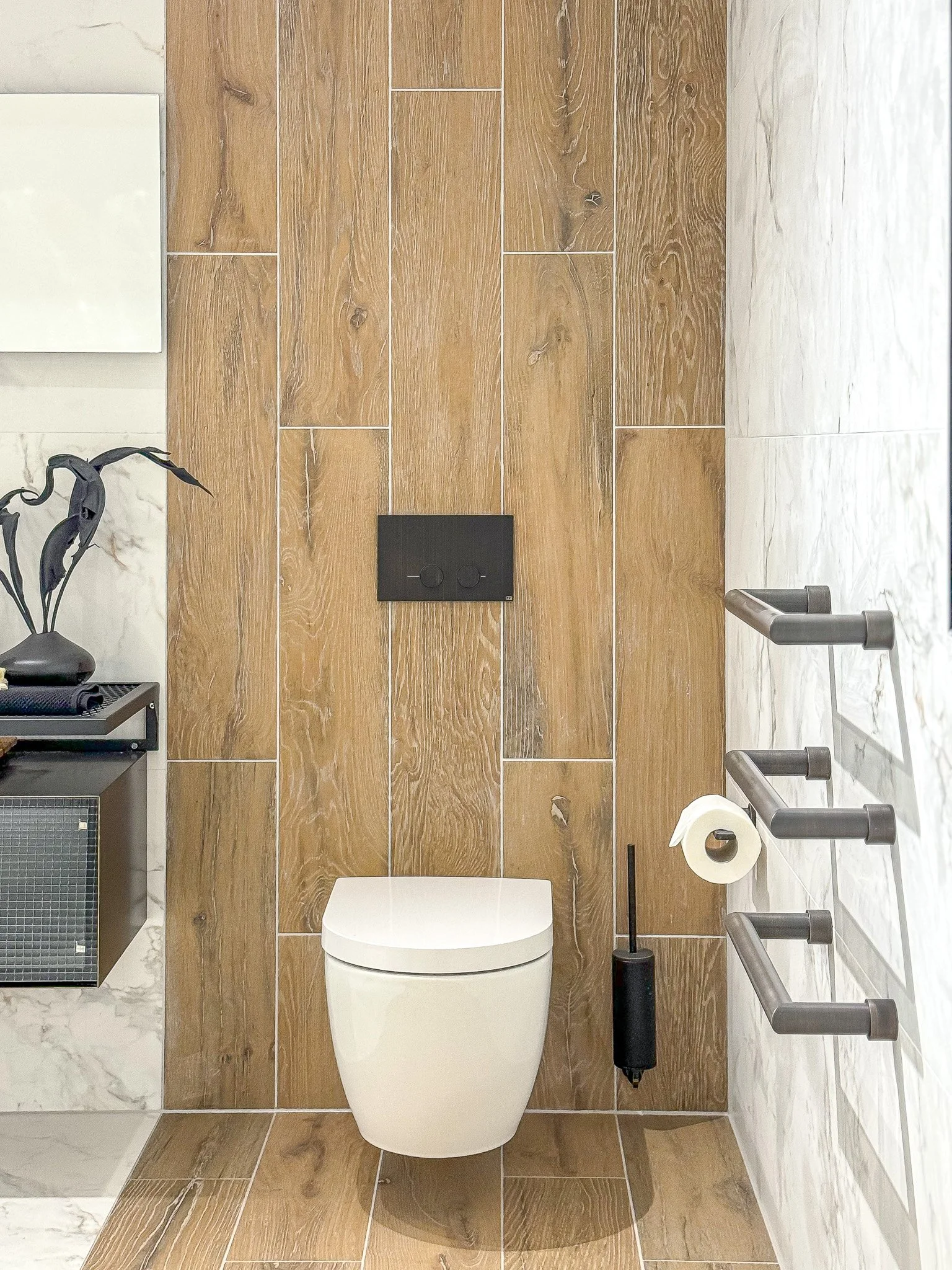 Wall-hung WC with wood-effect tiles and black flush plate in a modern North London bathroom
