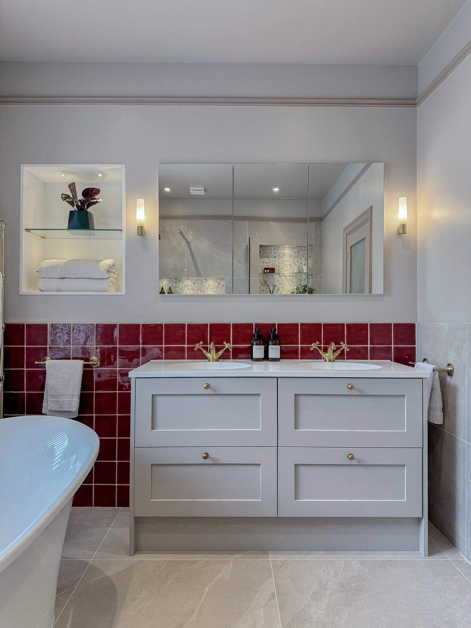 Bespoke double vanity bathroom with classic shaker cabinetry, brass crosshead taps, red glazed wall tiles and mirrored cabinets in a luxury traditional bathroom