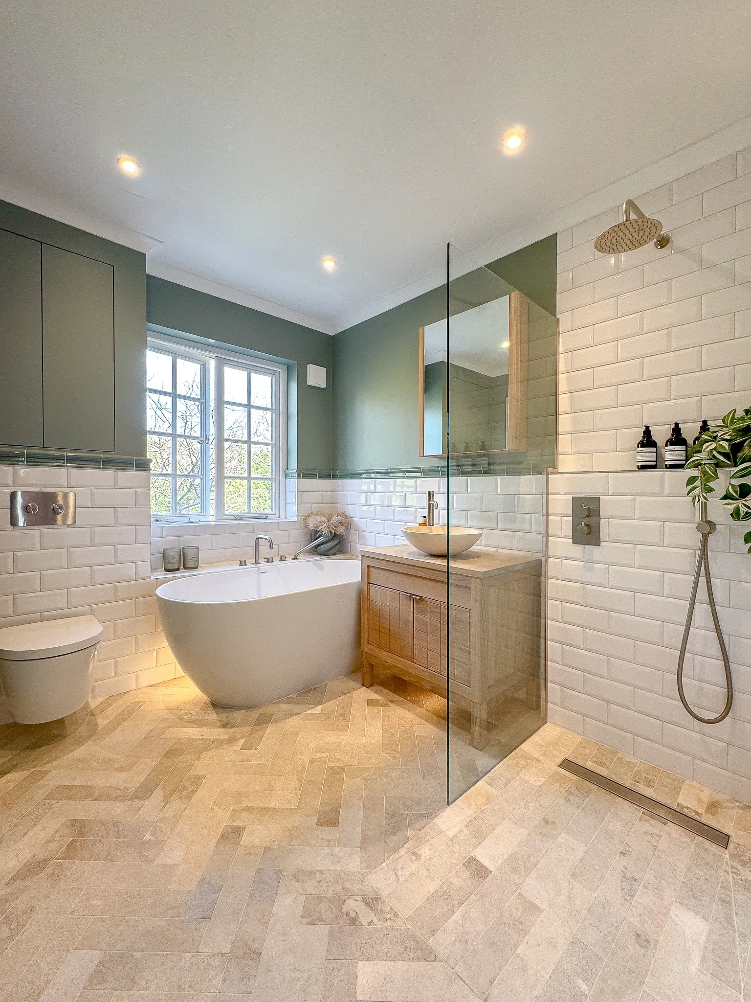 Light-filled family bathroom with freestanding bath, white metro tile walk-in shower, timber vanity unit and herringbone stone floor