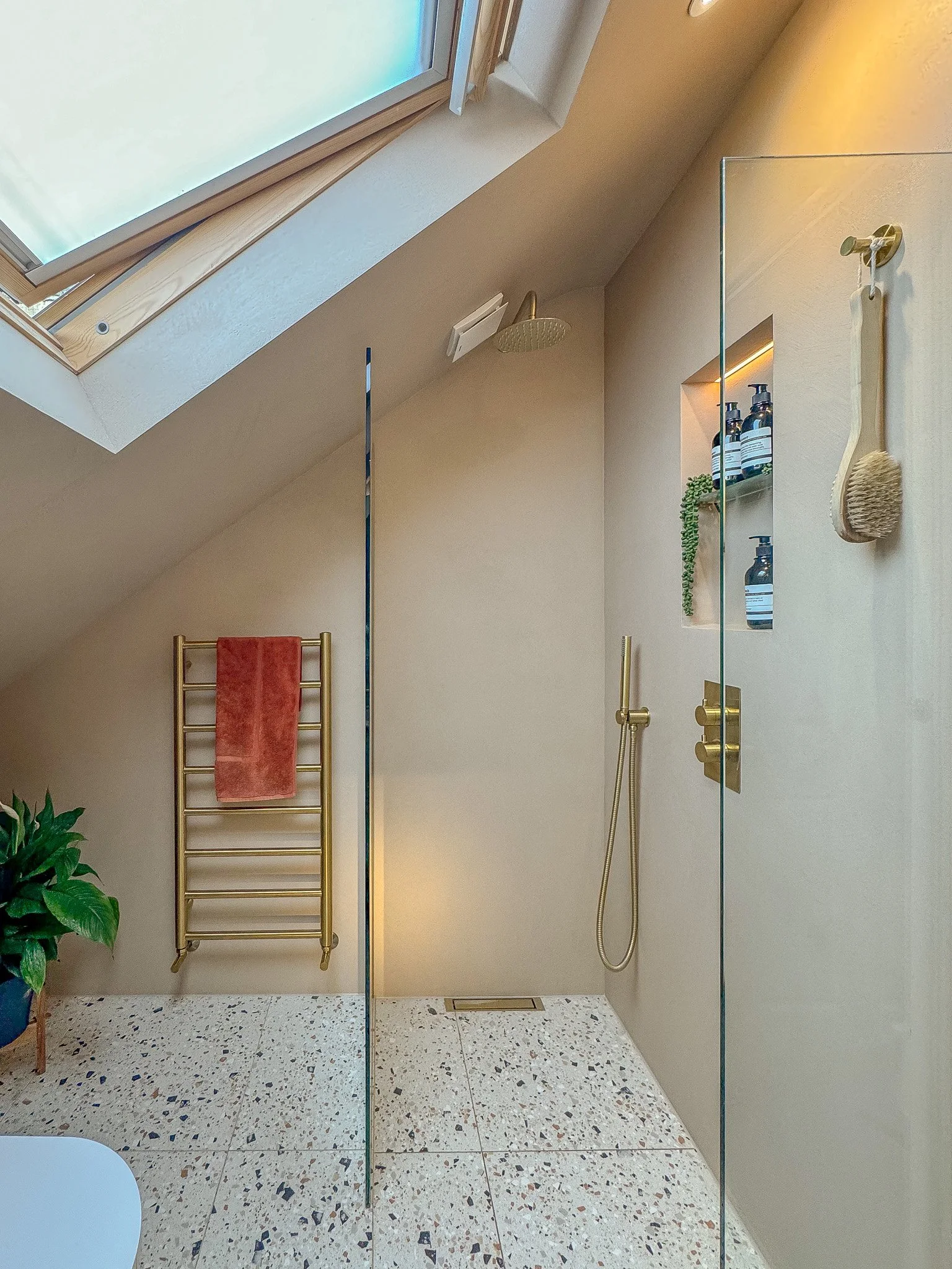 Walk-in shower with skylight, microcement walls and brushed brass shower fittings in North London