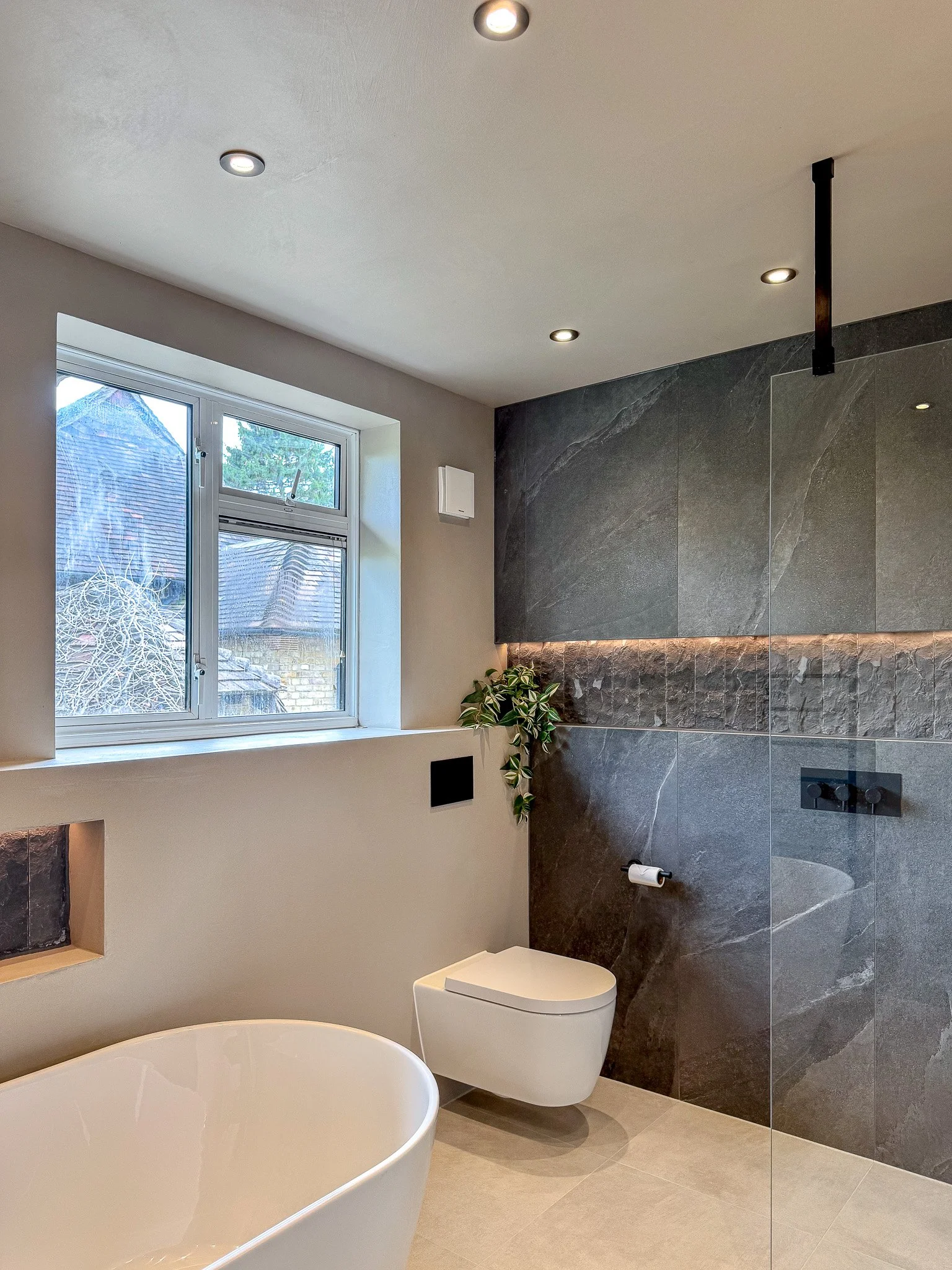 Elegant bathroom design with dramatic stone wall, soft ambient lighting and minimalist fixtures in a calm neutral palette.