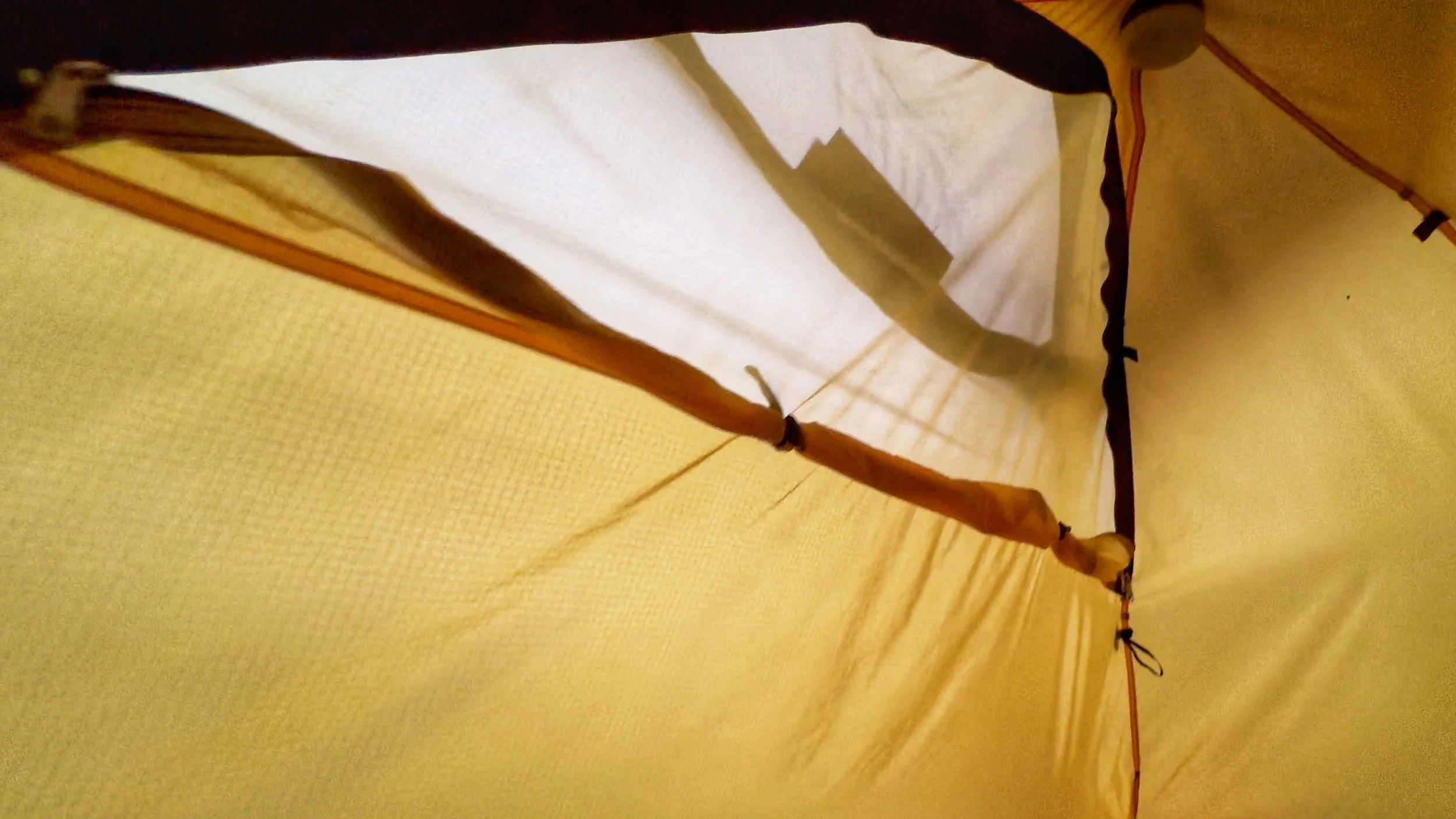 View from inside a yellow camping tent showing fabric and seam details.
