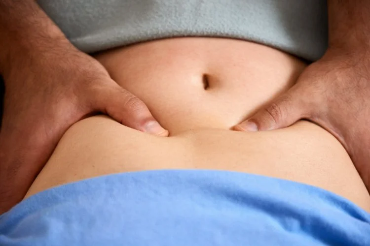 Nahaufnahme eines Bauches mit Händen, die ihn massieren.