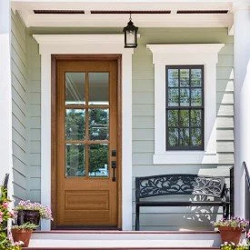 Front porch with a wooden door, window, and black bench.