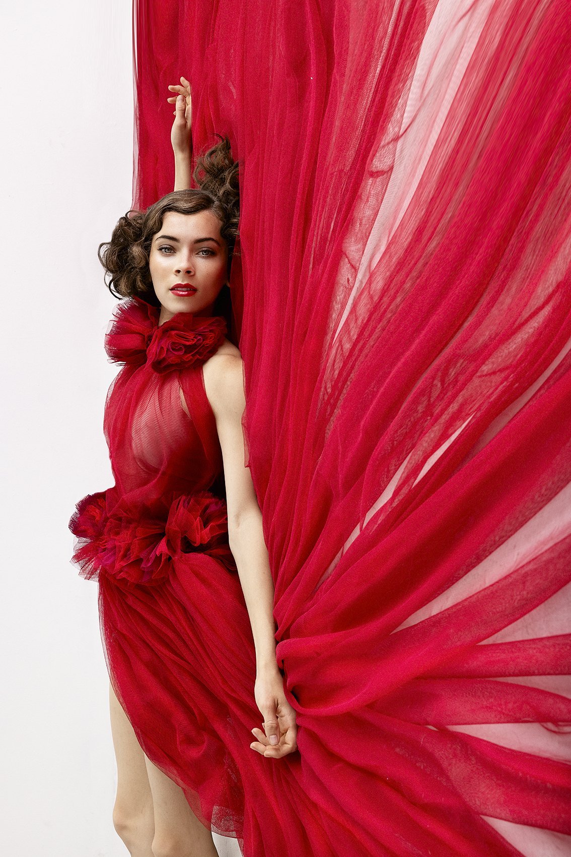 Woman leaning against a wall with a red dress spread out during Dance Photo Session with Beauclair Photography