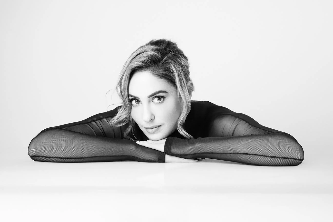 Women's portrait in white background of black and white beauty image.  Close up with chin resting on hands.