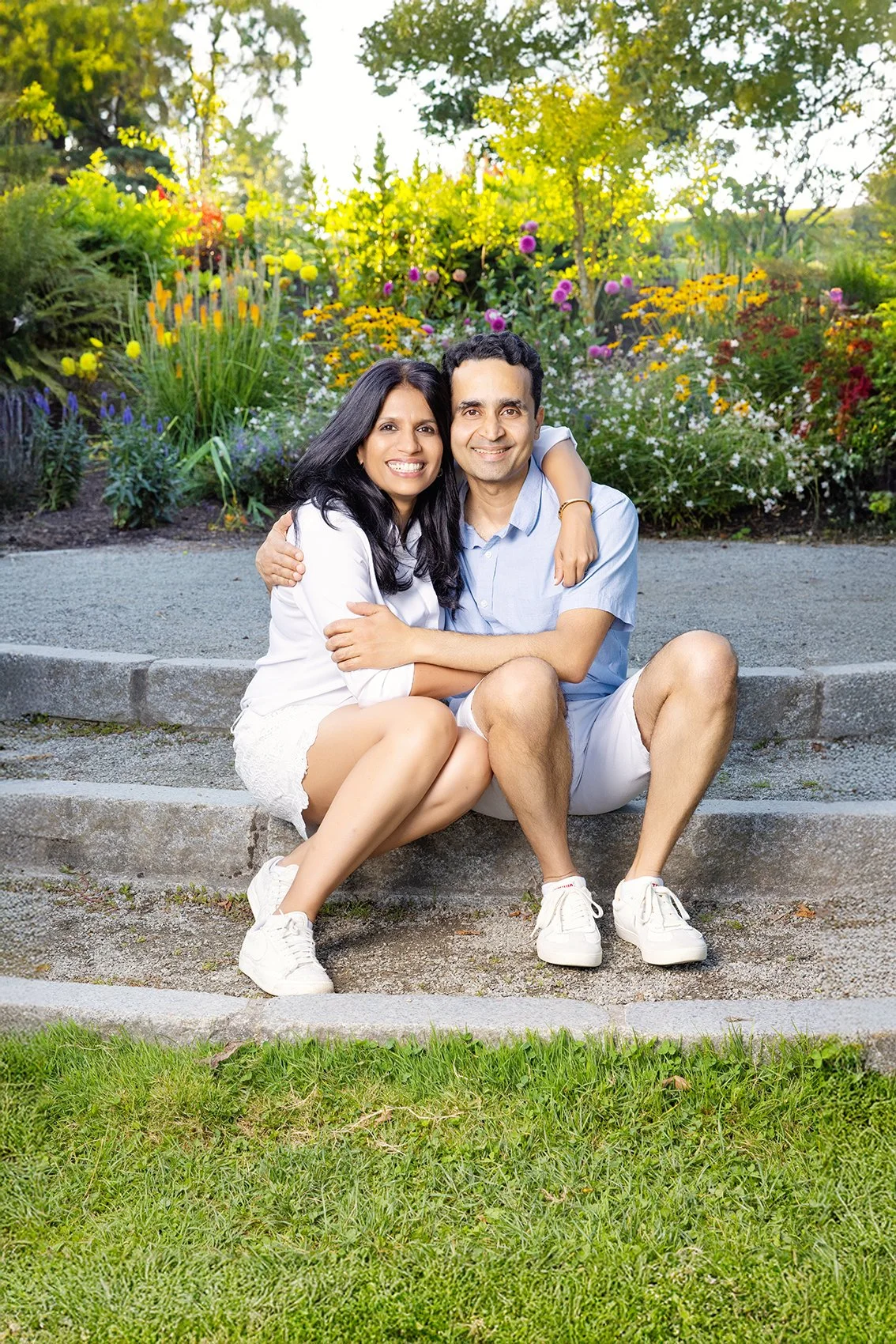 A smiling couple sitting on steps in a garden in Kirkland park near me