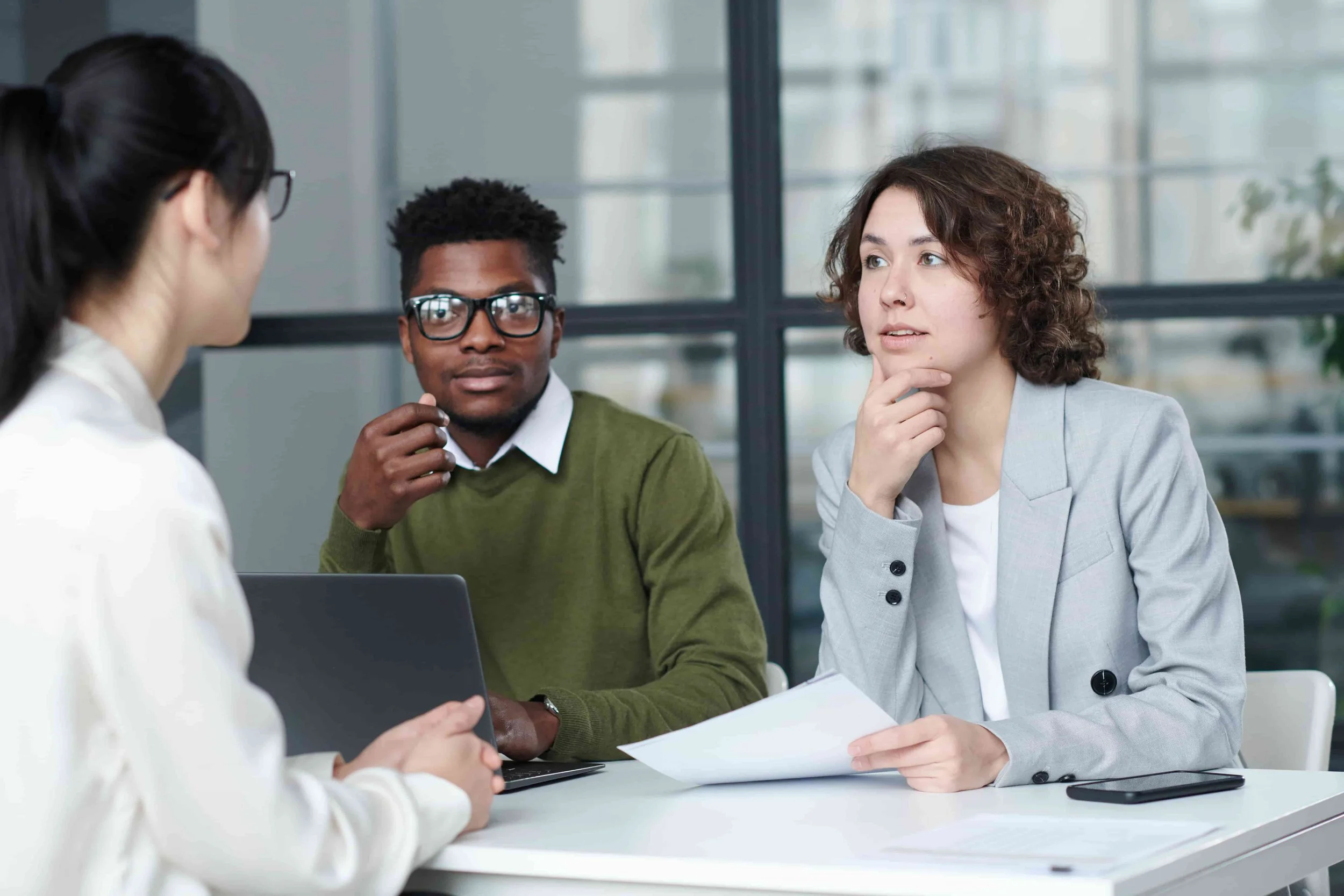 Three young professionals in a focused conversation.