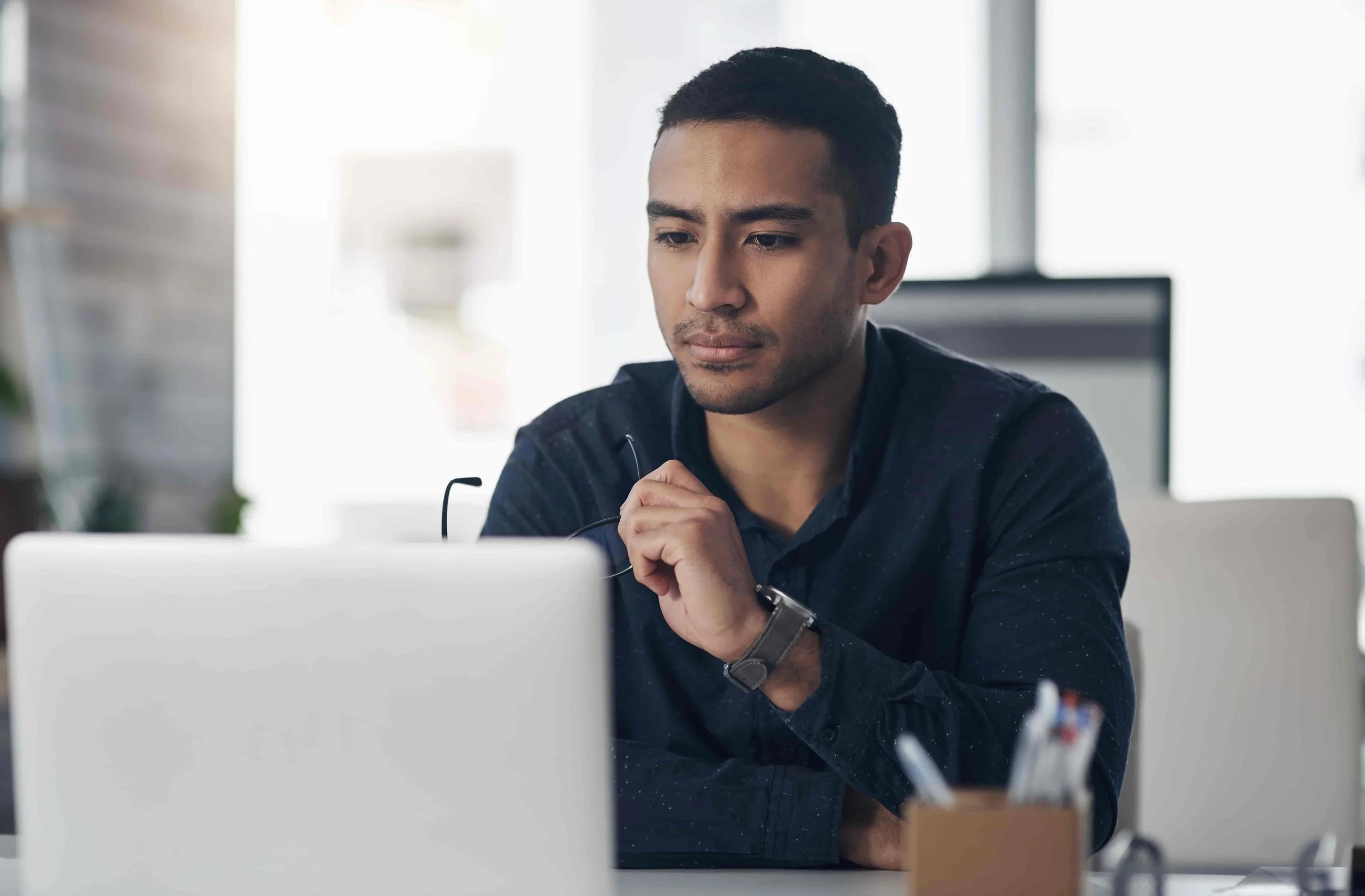 Man with eyeglasses working on a laptop at a desk