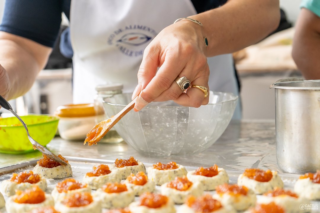 A cafeteria kitchen worker placing freshly prepared plant-based food onto a serving counter in a brightly lit school dining hall.