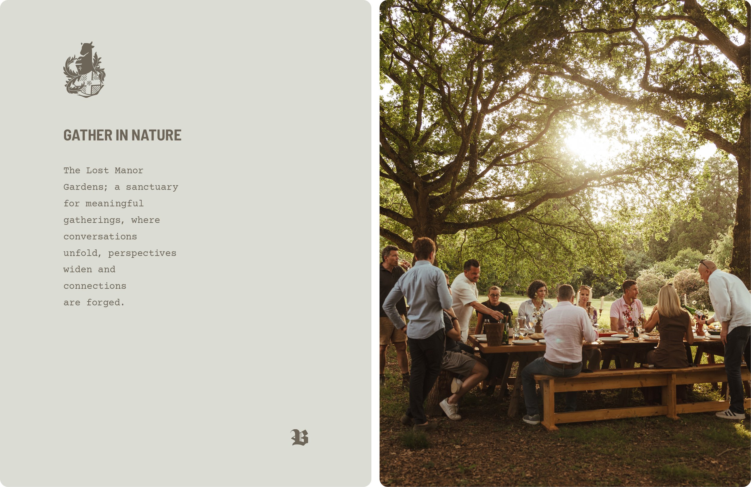 A group of people gathered outdoors under large leafy trees for a social event, with some standing and some sitting at a long wooden table, enjoying food and drinks during the daytime.