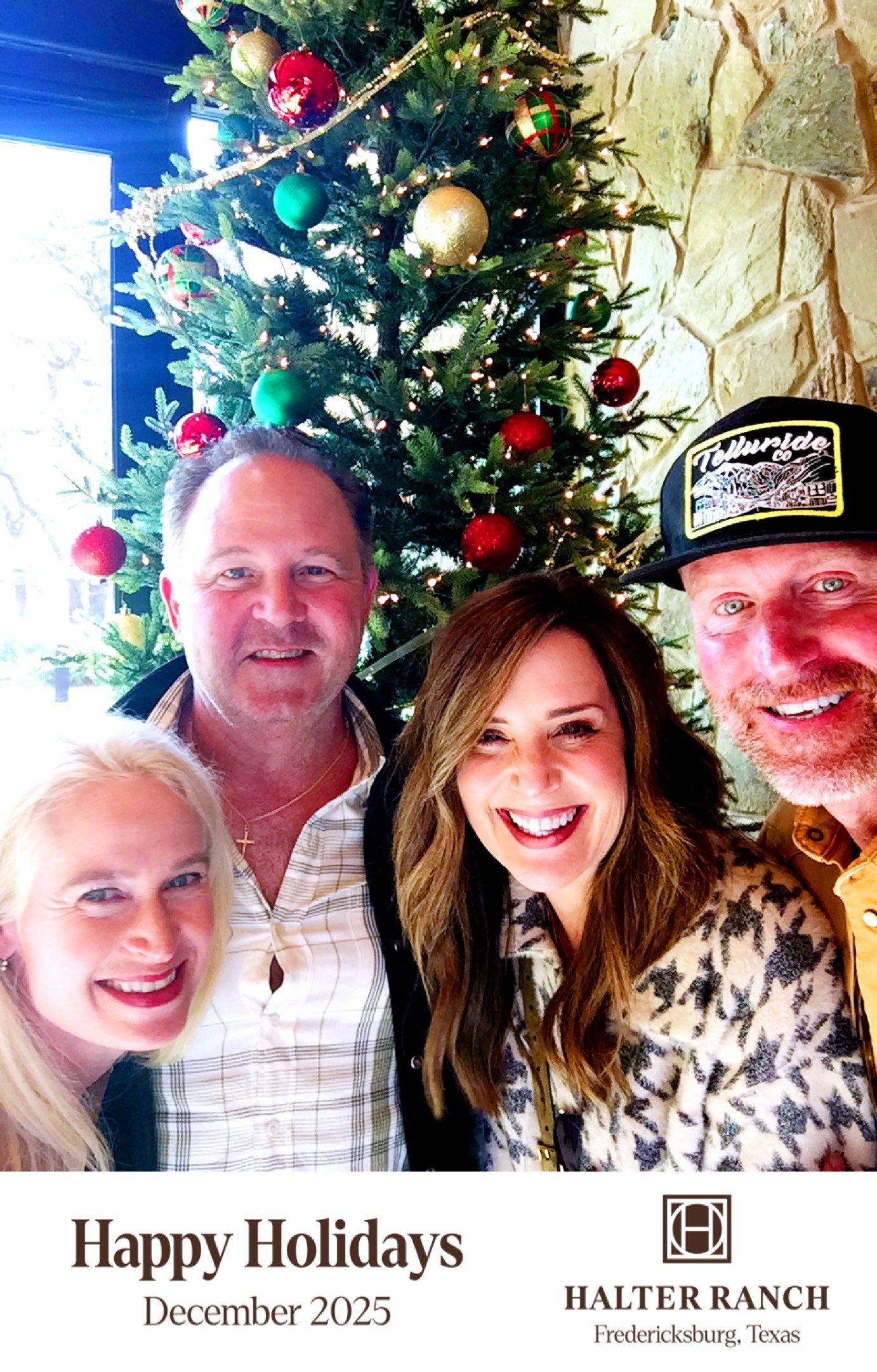 A group of four smiling people taking a selfie in front of a decorated Christmas tree inside a house with stone walls. The group includes two women with blonde and brunette hair, and two men with short hair, one wearing a cap. The photo is part of a holiday greeting card from Halter Ranch winery in Fredericksburg, Texas, printed with "Happy Holidays December 2025."