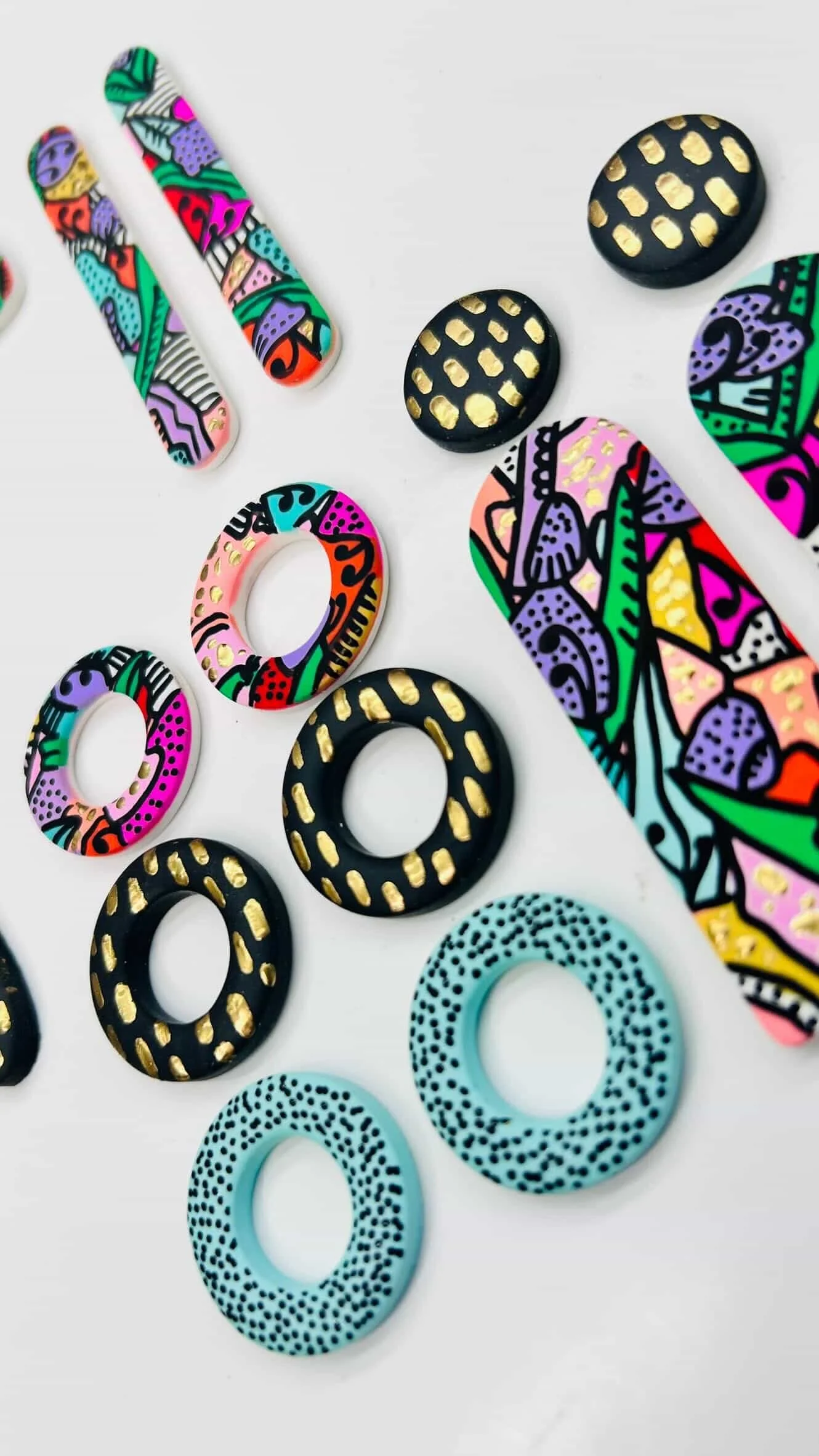 Colorful and patterned hair accessories, including hair clips, rings, and bobby pins, with a mix of abstract, polka dot, and geometric designs in vibrant colors.