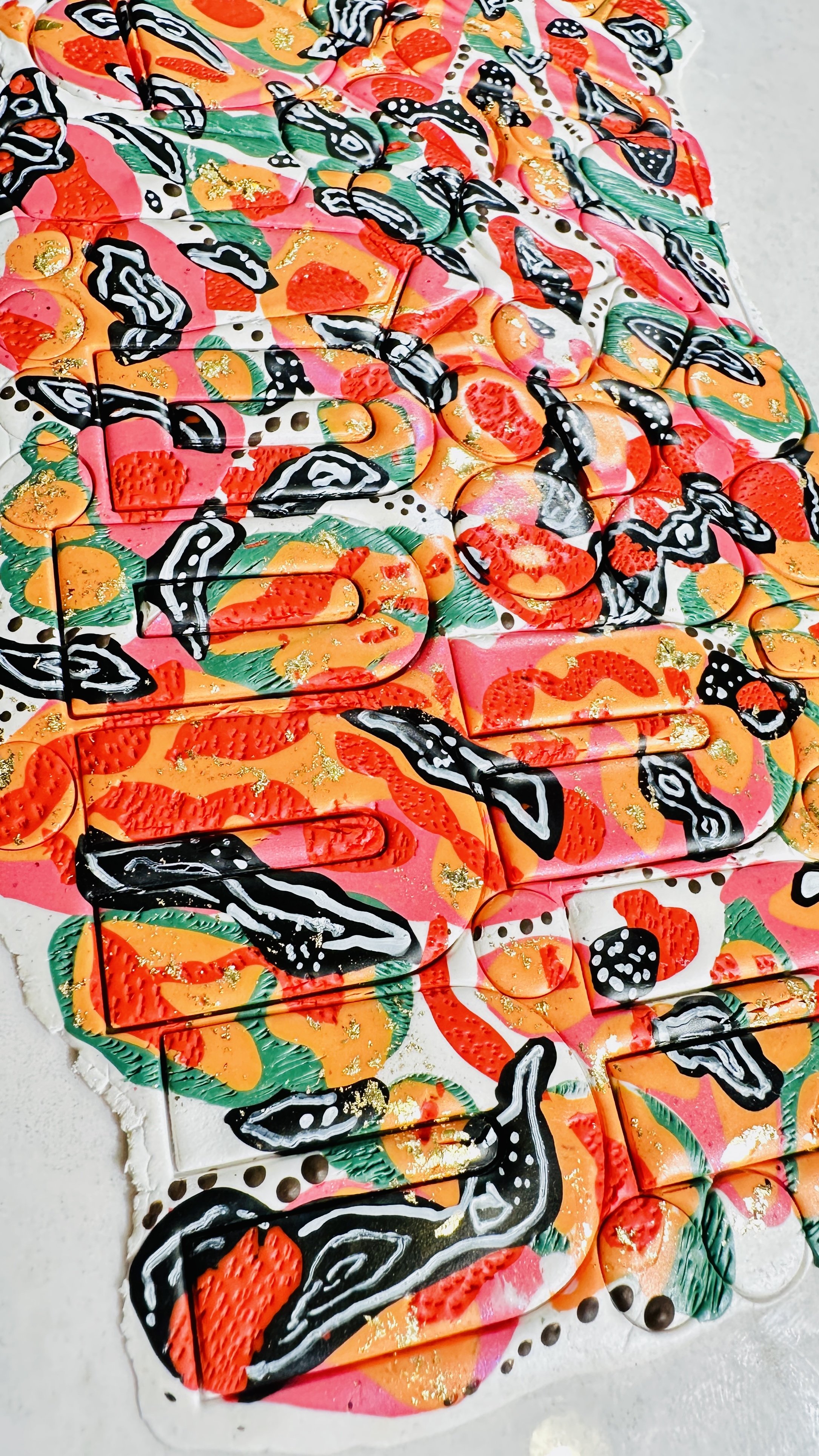 Colorful abstract art mural with orange, pink, black, green, and gold details, featuring shapes and patterns.