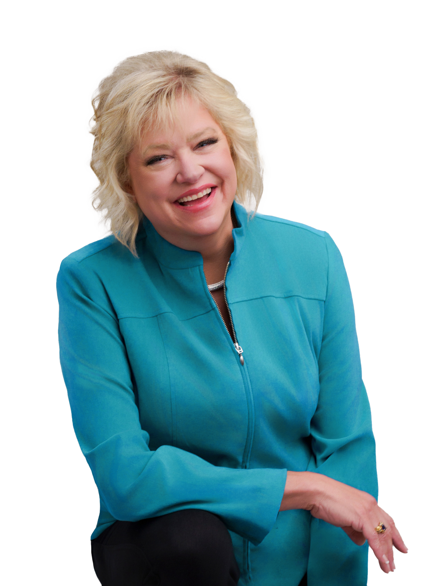 Portrait of a smiling blonde woman with short hair, wearing a bright blue zip-up jacket, sitting and leaning slightly forward.
