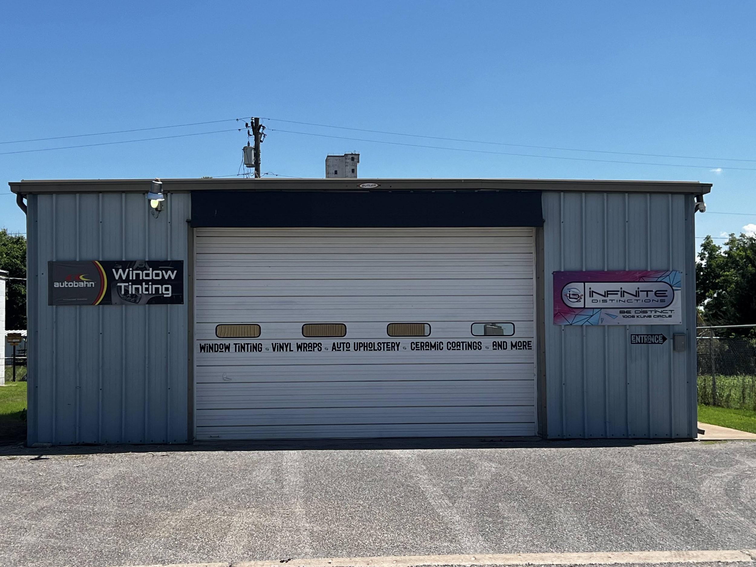 This image shows the exterior of the Infinite Distinctions location, a large, single-story building with two garage doors, surrounded by several parked cars.