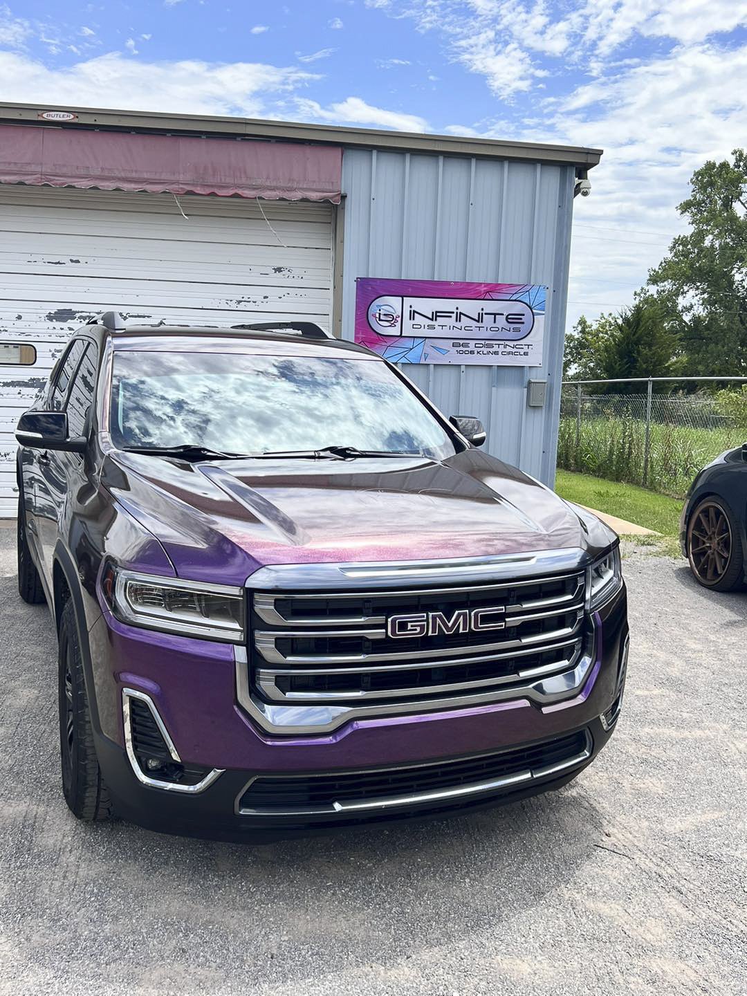 A GMC truck, featuring a vibrant purple wrap, is shown parked outside the Infinite Distinctions location in Enid, Oklahoma.