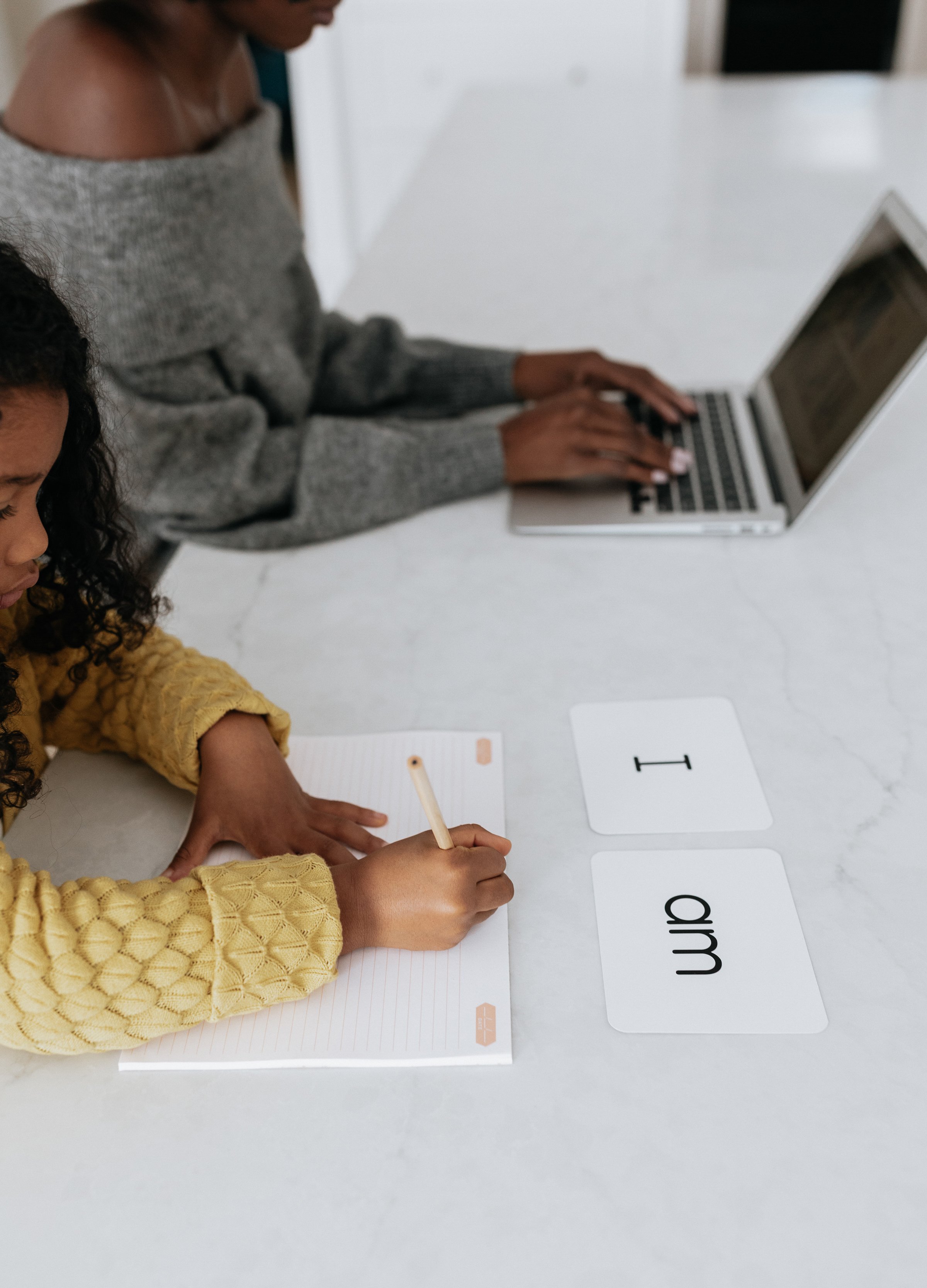 Adult and child working at a table with a laptop and flashcards
