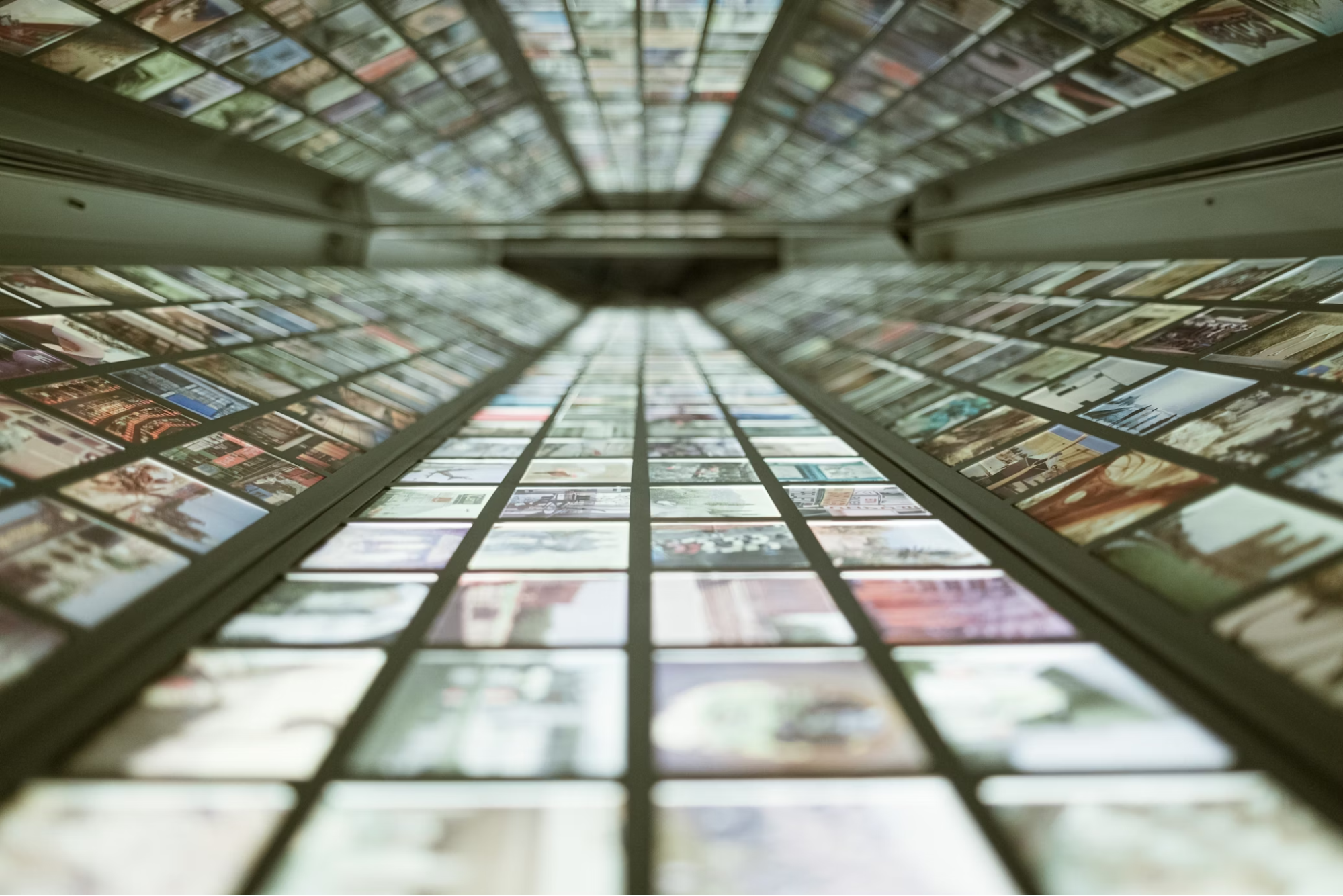A deep perspective view down a corridor of glowing digital panels, each displaying a grid of photos and graphics.