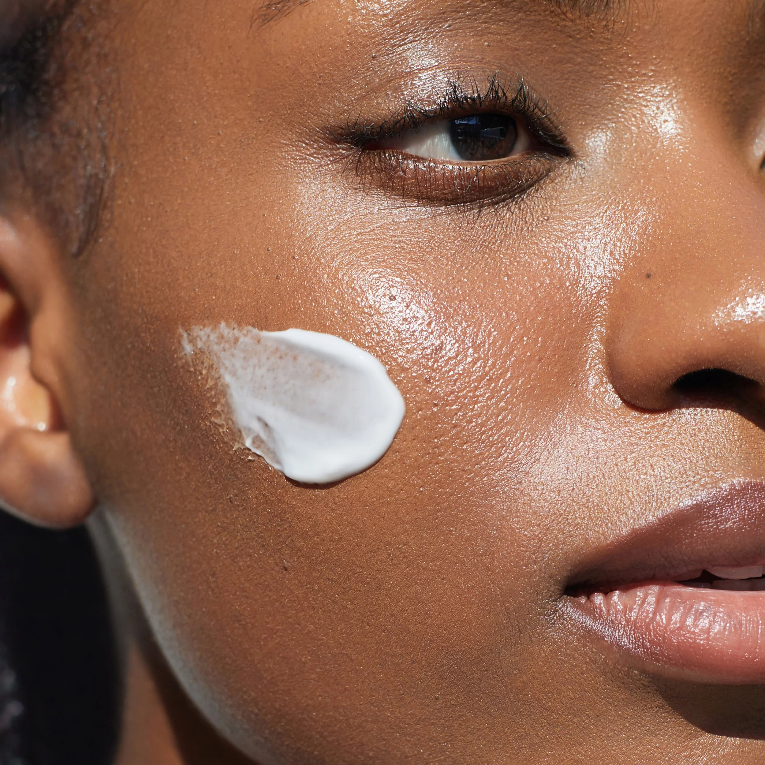 Close-up of a woman's face with moisturizer on her cheek