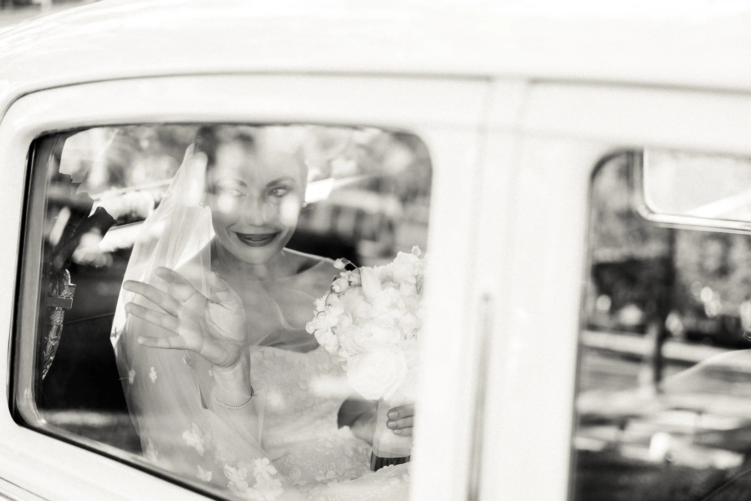 Boca Grande Bride smiling through the window of a vintage wedding car while holding her bouquet before her wedding ceremony.