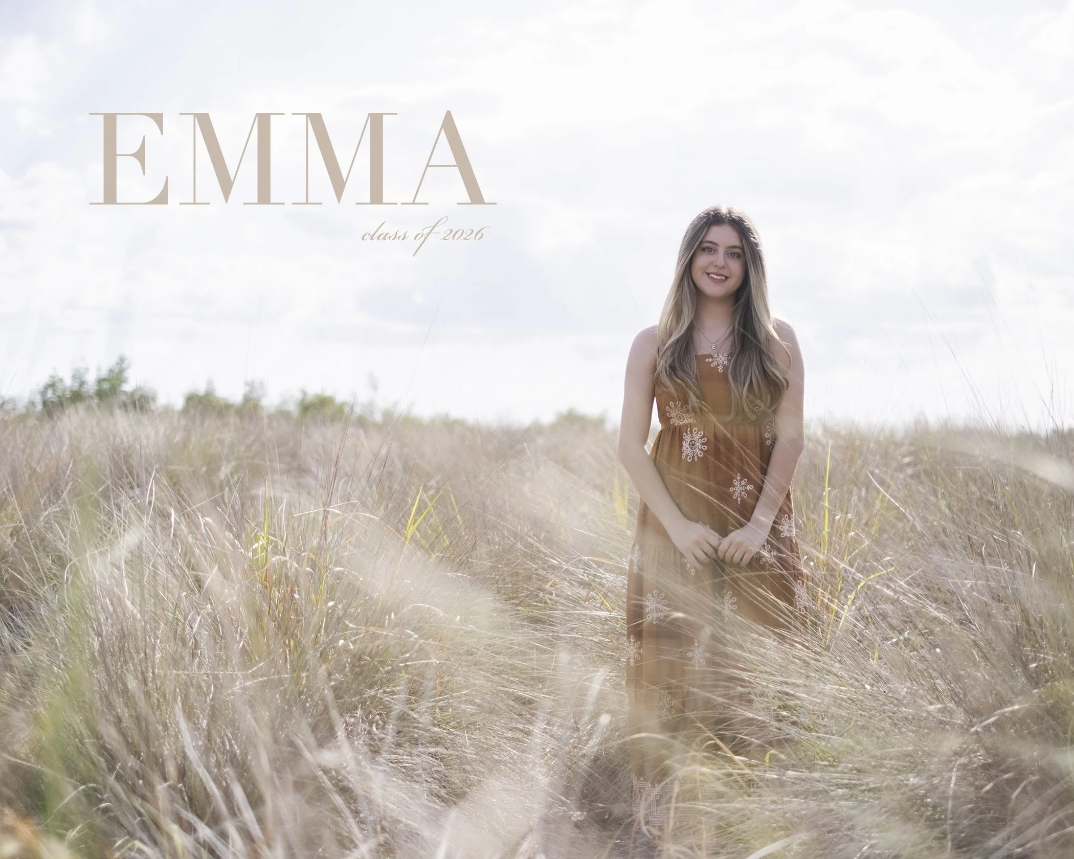 A young woman with long blonde hair, wearing a brown dress with white embroidery, standing in a field of tall grass under a partly cloudy sky.