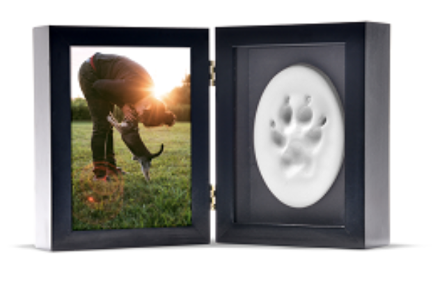 Two-panel frame with a photo of a person bending down to a dog on the left and a paw print impression on the right.
